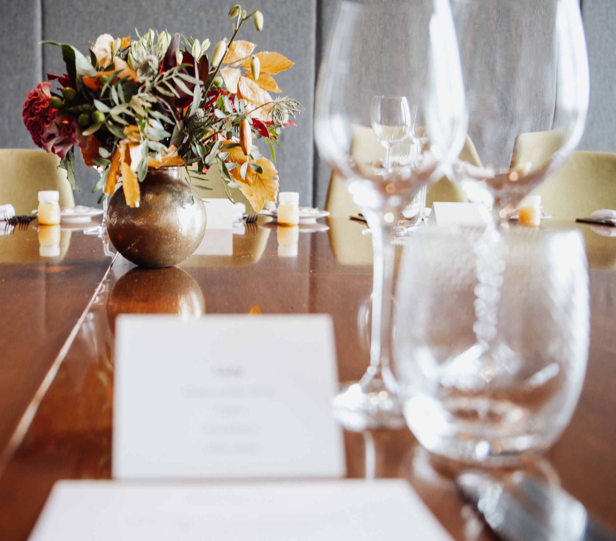 Elegant dining table setup with a floral centerpiece, wine glasses, and place cards.