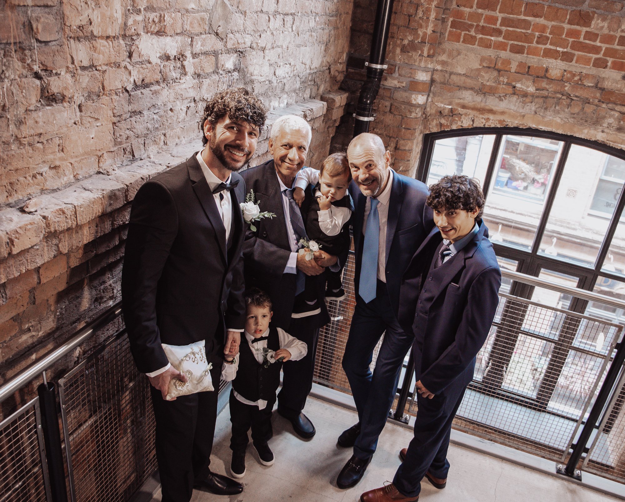 Group of men and boys in formal attire standing on a staircase.