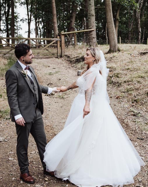 Bride and groom holding hands in a forest setting.