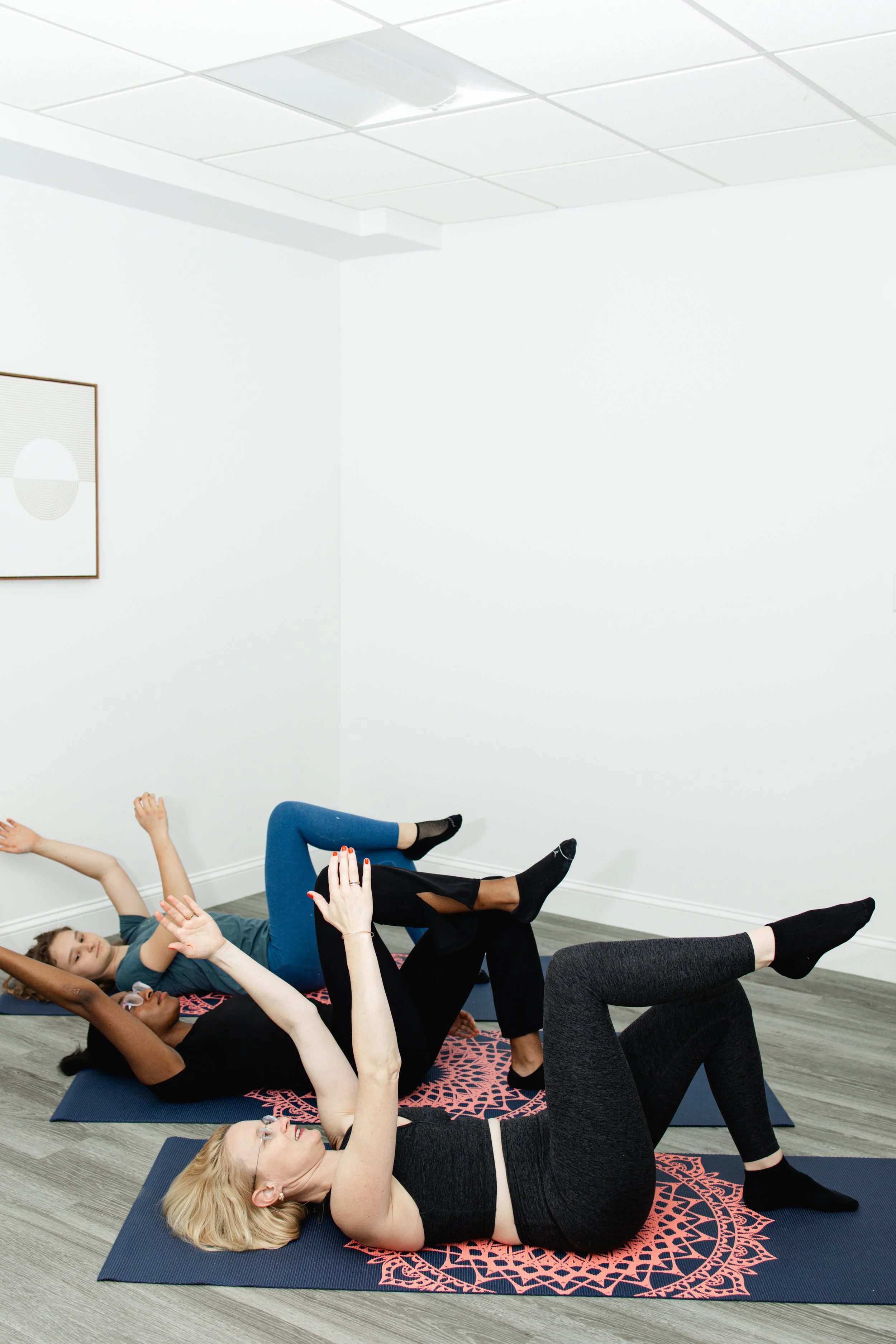 Pilates class practicing dead bug exercise on pilates mats