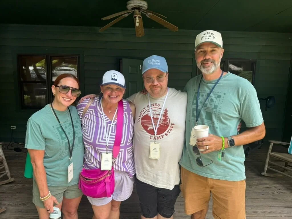 Four friends smiling on a cabin porch at Hope Heals Camp.