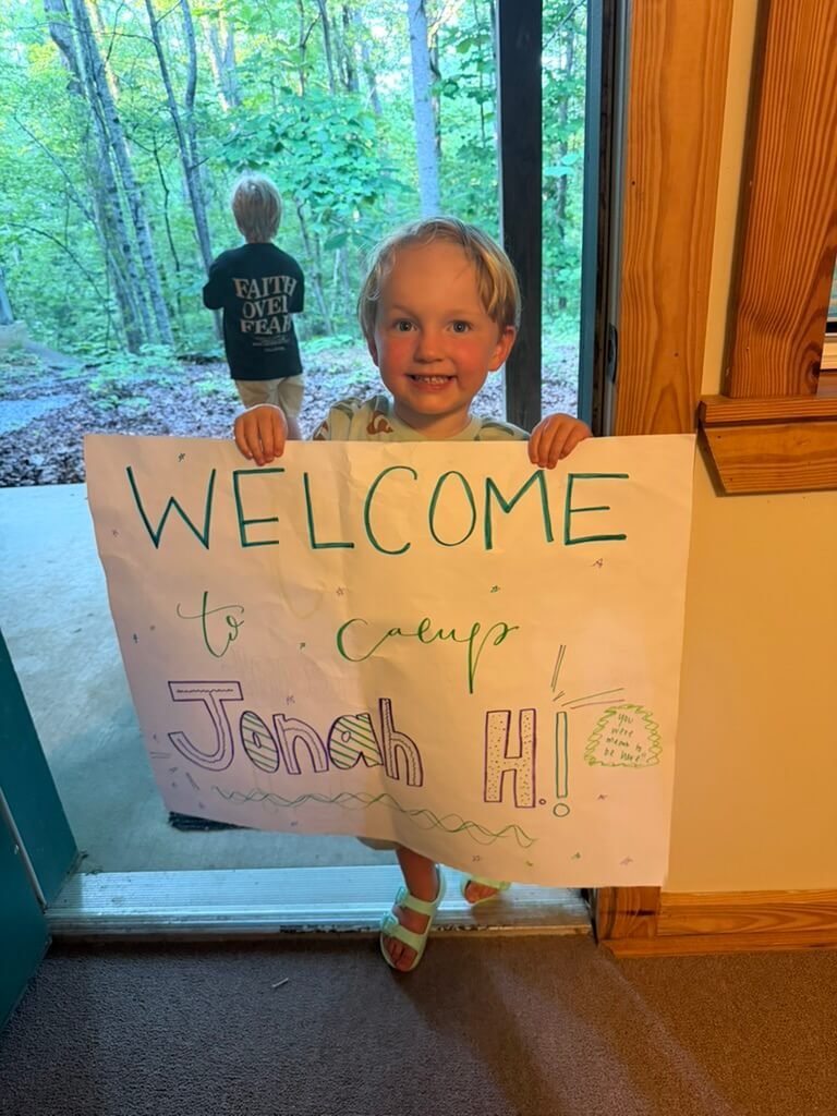  A boy holding a handmade welcome sign at a Hope Heals Camp cabin. 