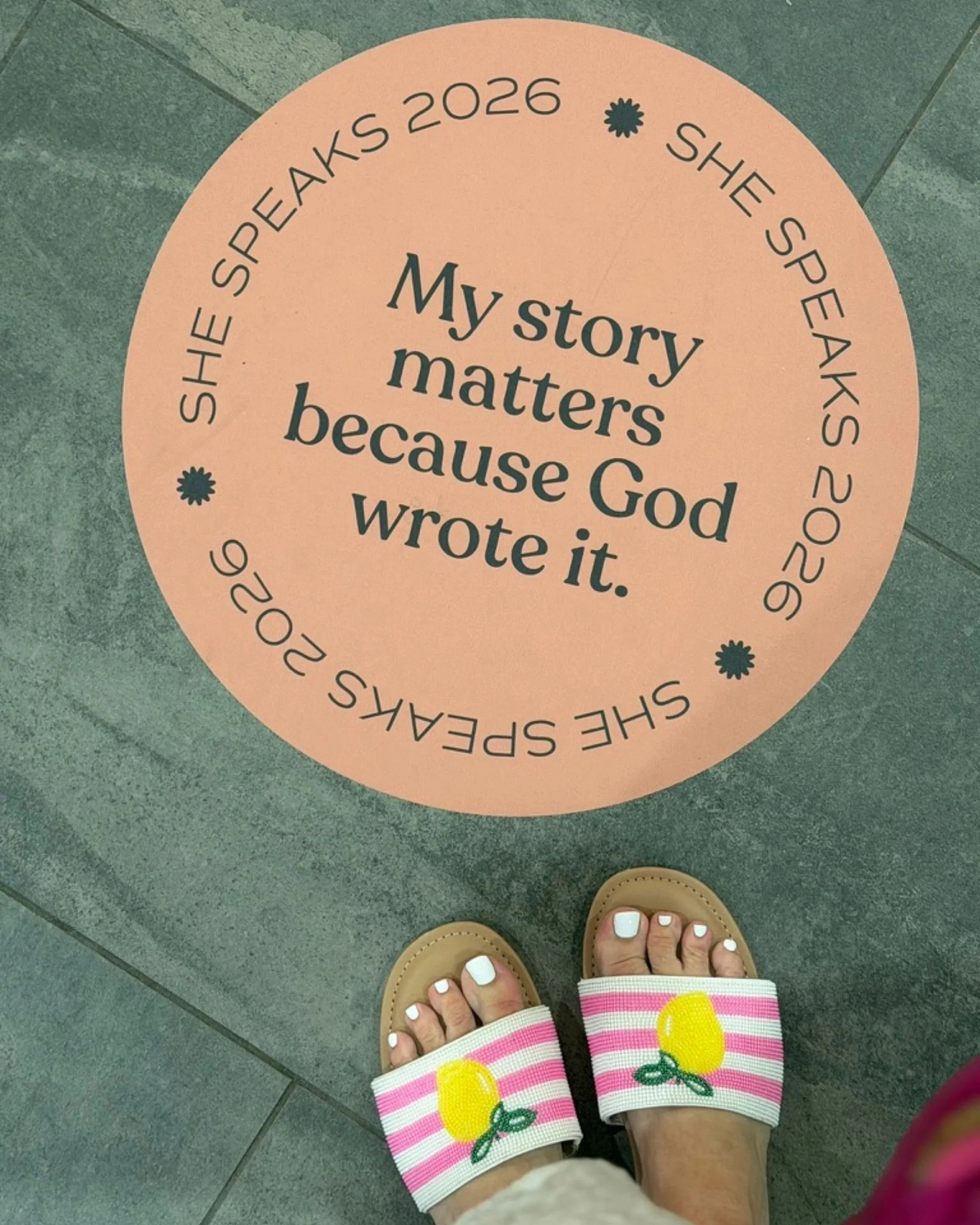 A She Speaks 2026 floor decal reading "My story matters because God wrote it."