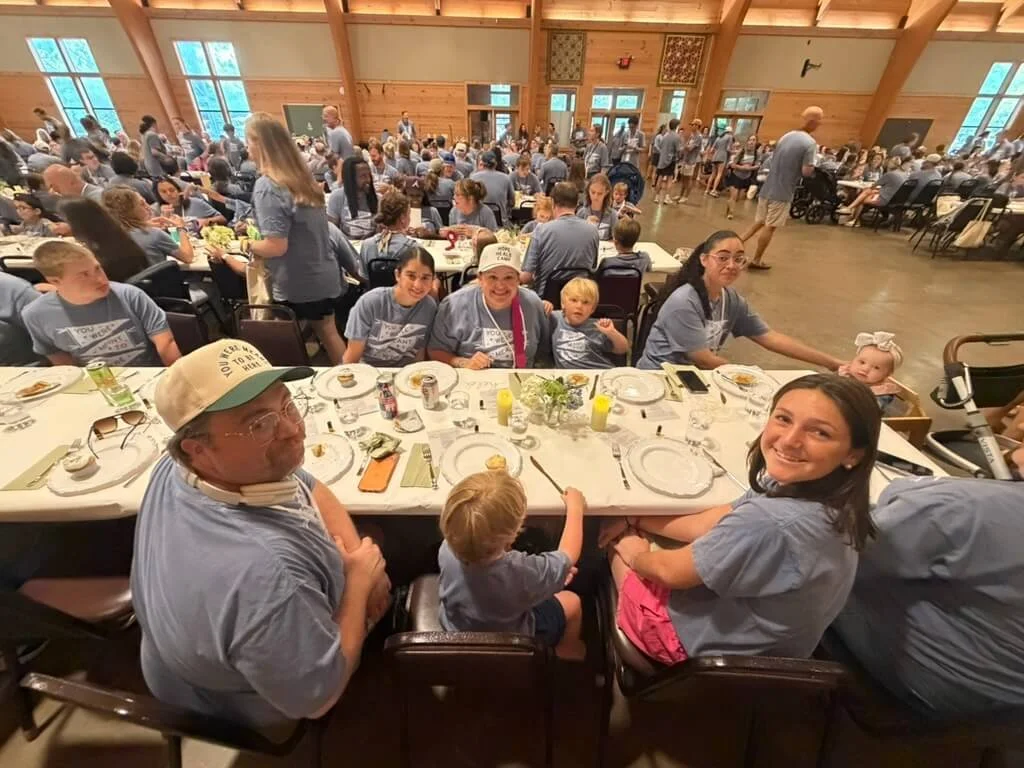 Families gathered at long dining tables inside the Hope Heals Camp dining hall.