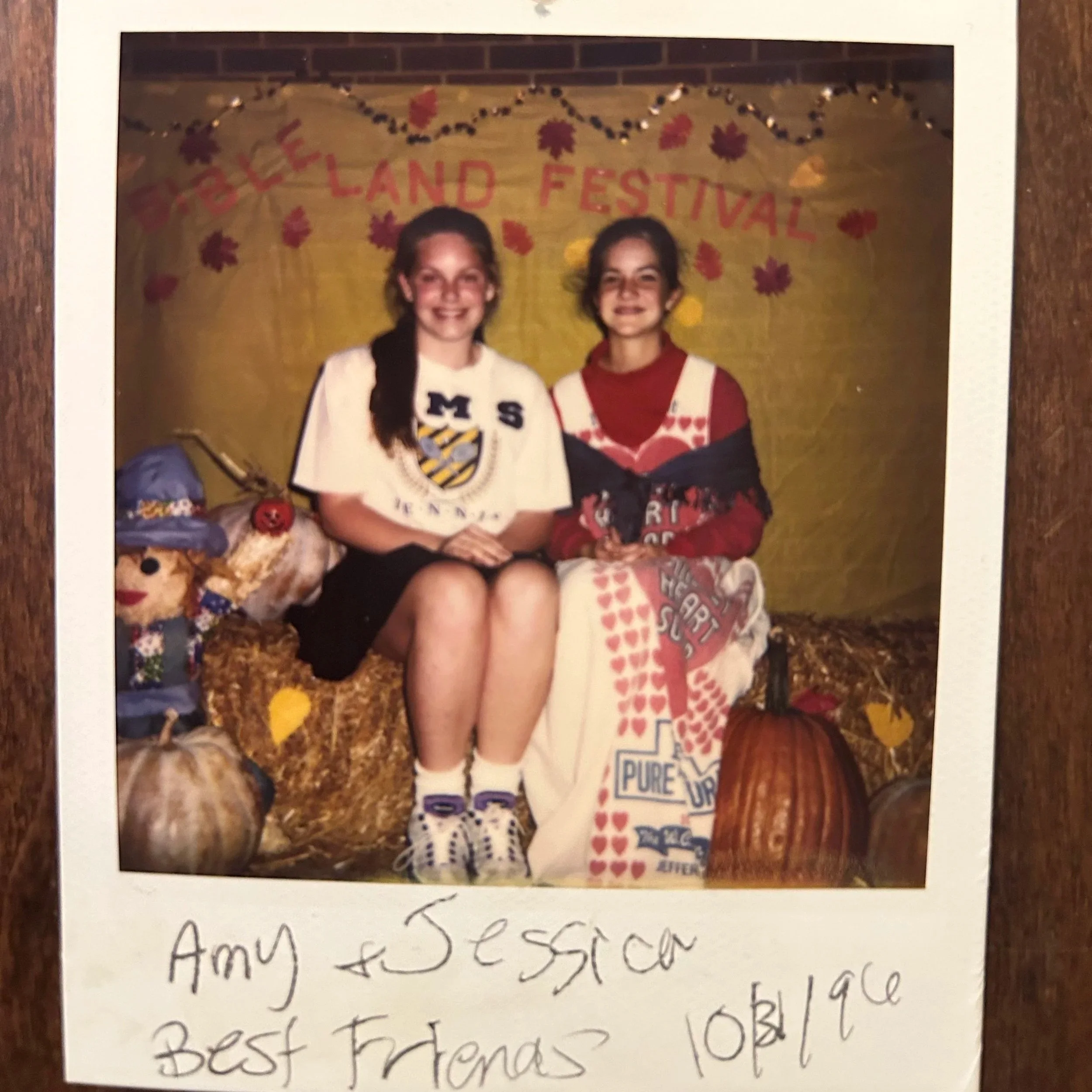 A faded Polaroid of two young best friends at a fall festival, pumpkins nearby.