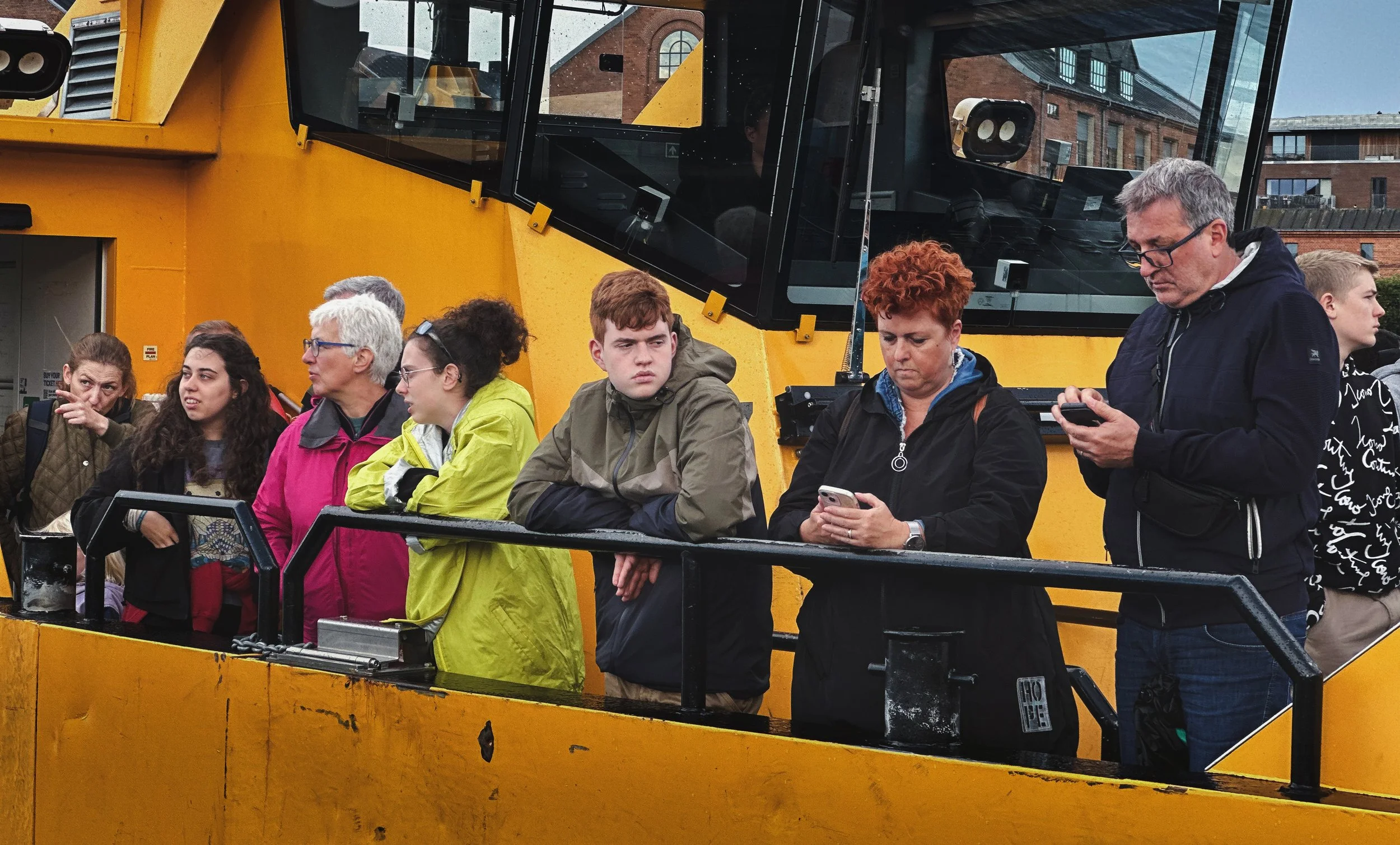 Passasjerer står langs rekka på en gul rutebåt i København