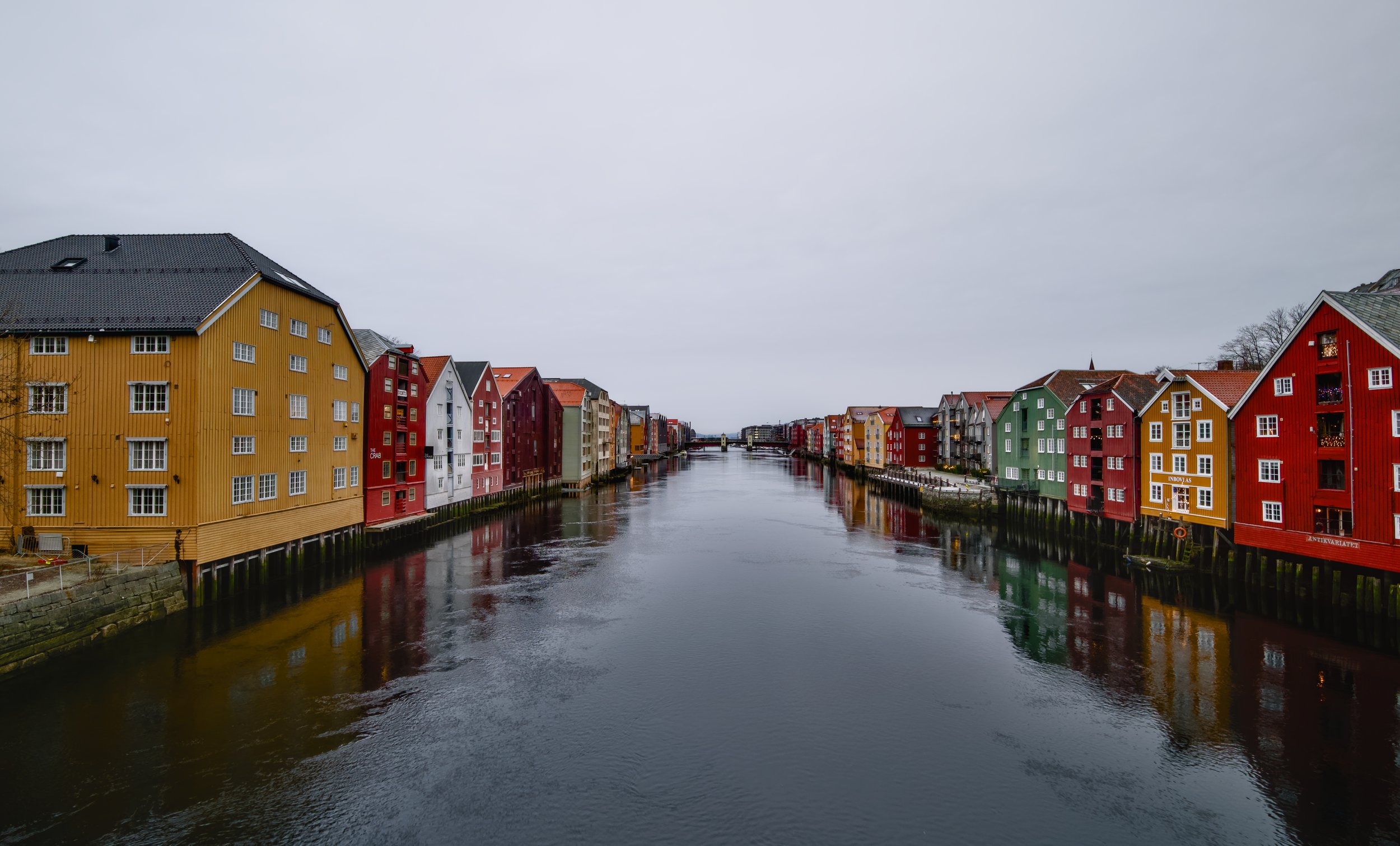Colorful waterfront buildings along a canal on a cloudy day in Trondheim, Norway. 
