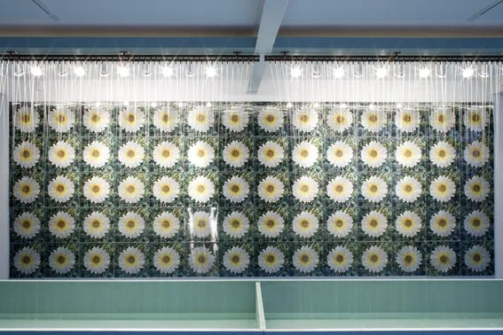 Detail view of the Andy Warhol installation, Rain Machine: Daisy Waterfall. It consists of a wall of lenticular prints of daisies, viewed through a rain fountain.