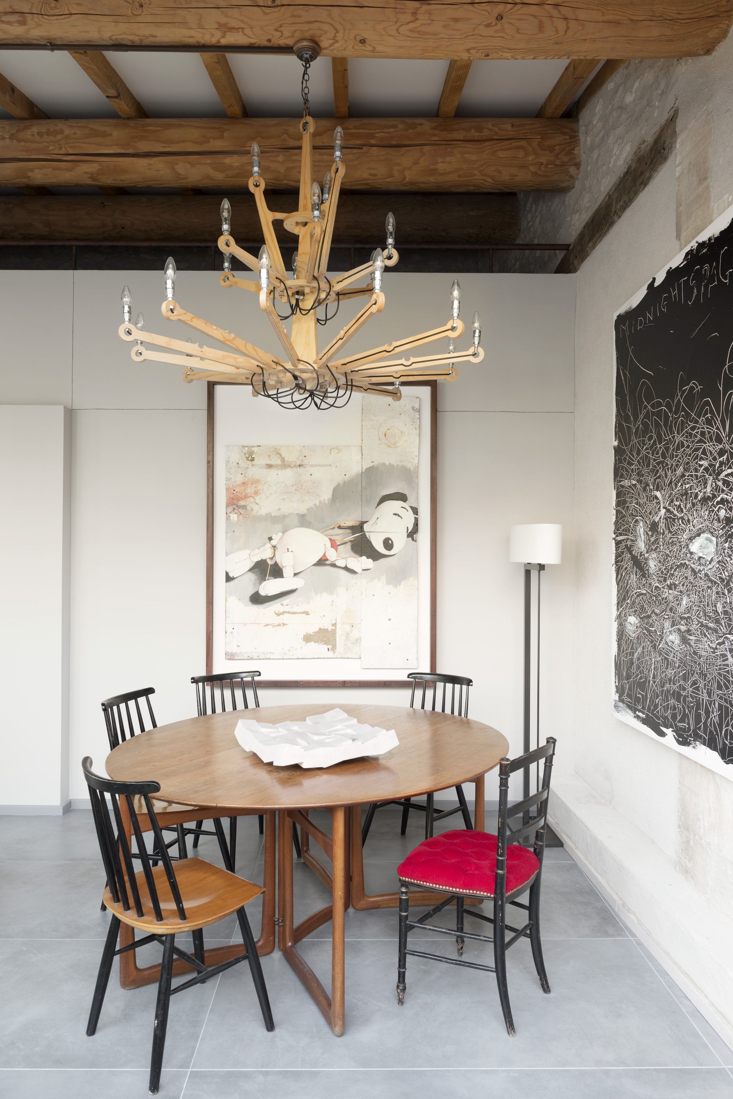 Detail of the dining area with a mid-century teak table, mix of chairs and plywood chandelier by Piet Hein Eek hanging above.