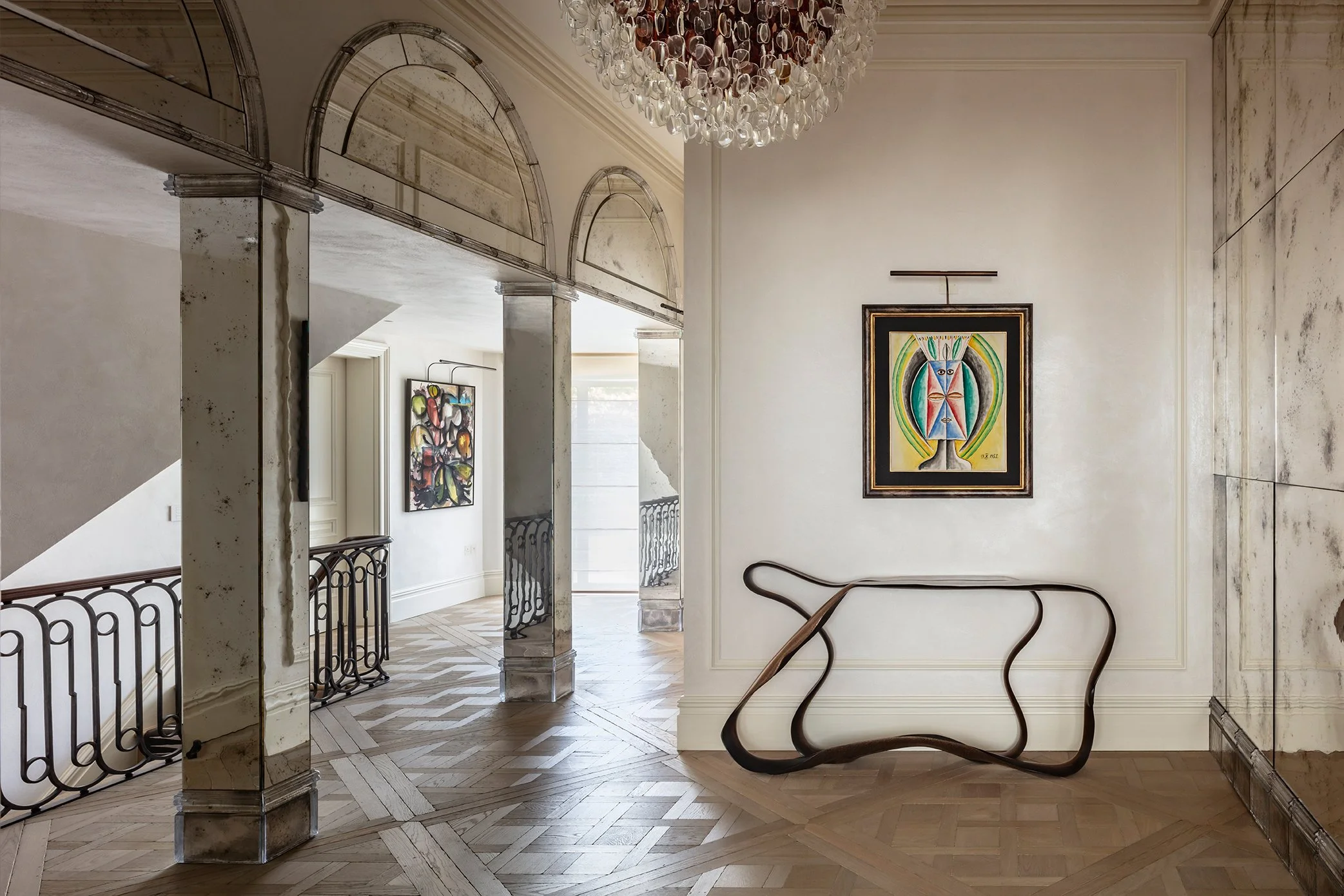 Interior photo of a en elegant transitional space featuring a sculptural console table, modern art and antique mirror architectural features