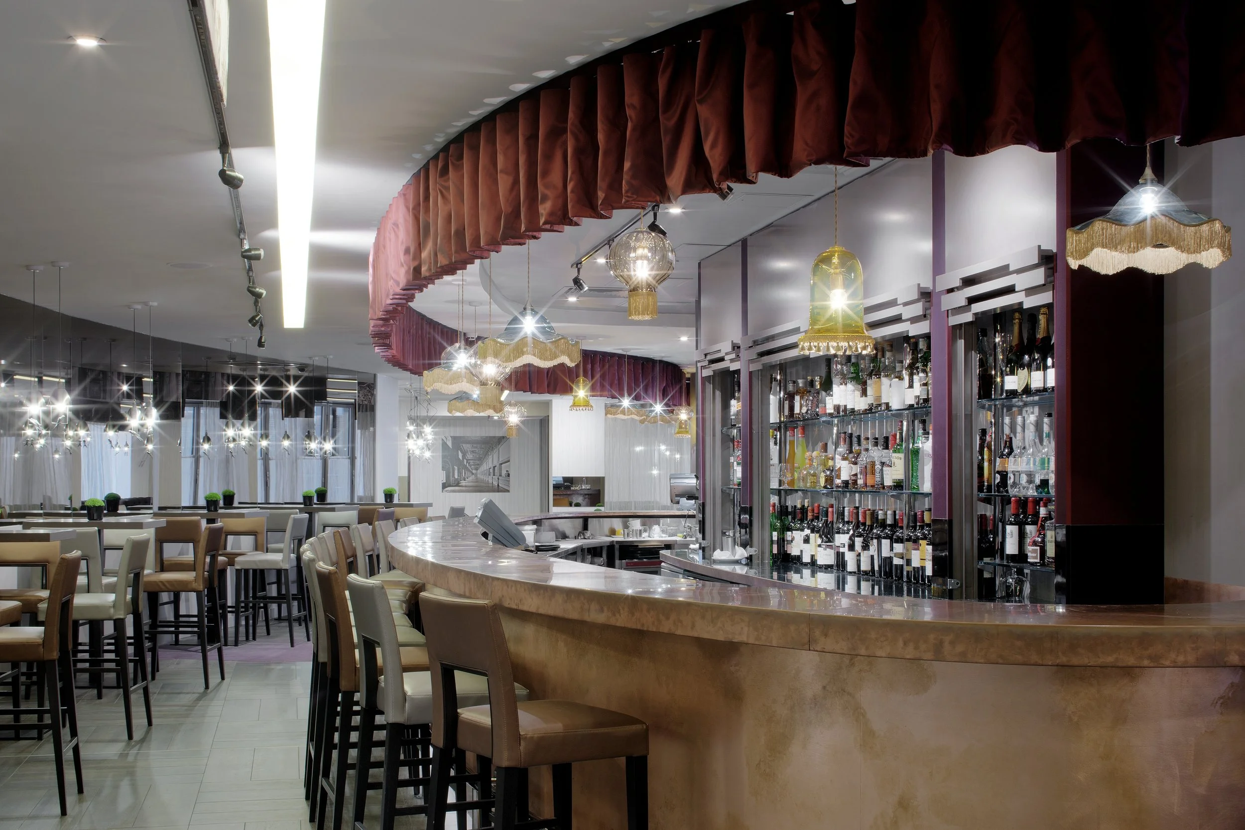Detail view of the curved copper-clad bar with a pleated red satin pelmet curtain curving in line with the bar.