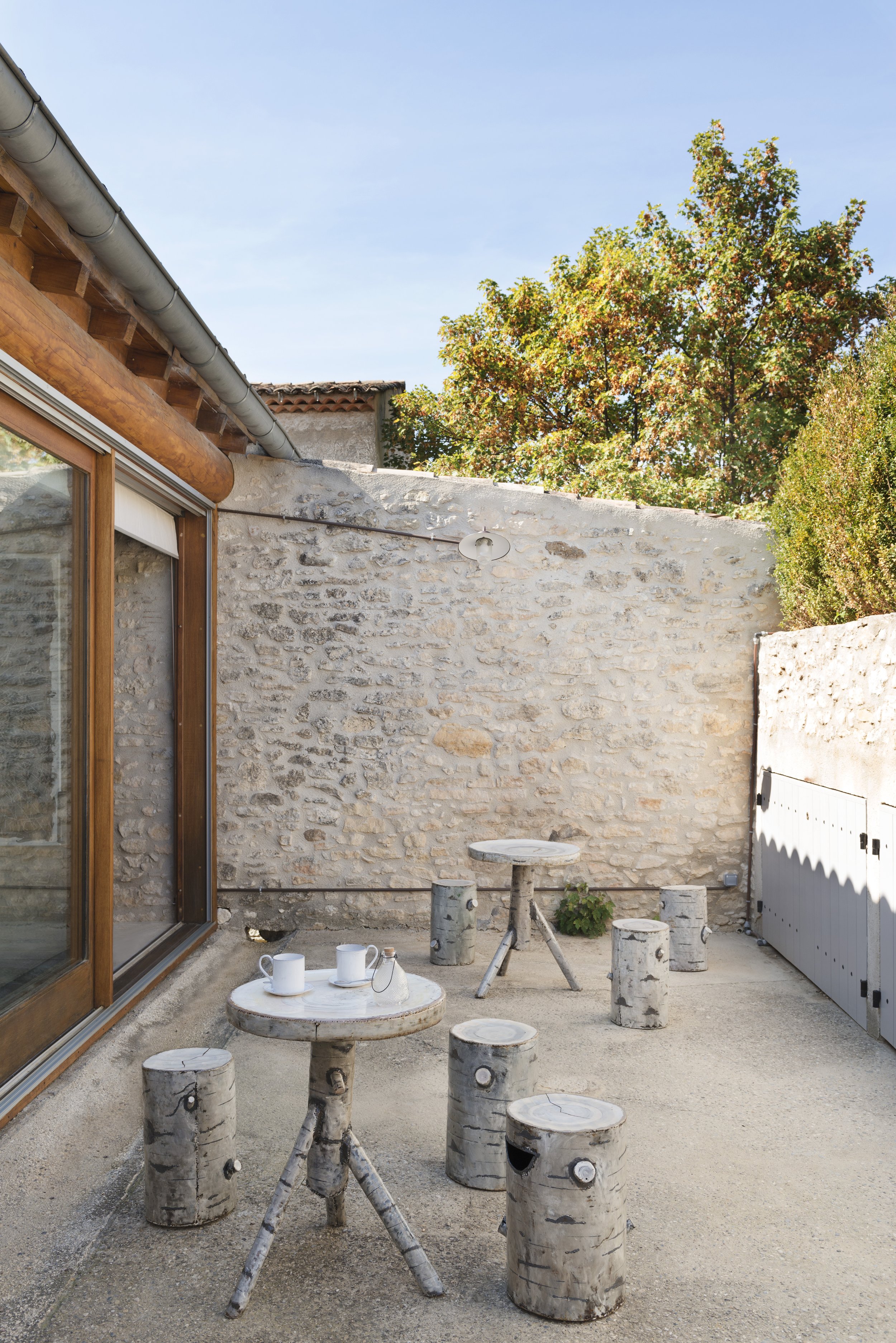 View of the walled courtyard with trompe-l'œil metal furniture pained to look like stumps of Birch trees, with the tables appearing to be constructed of Birch tree branches.