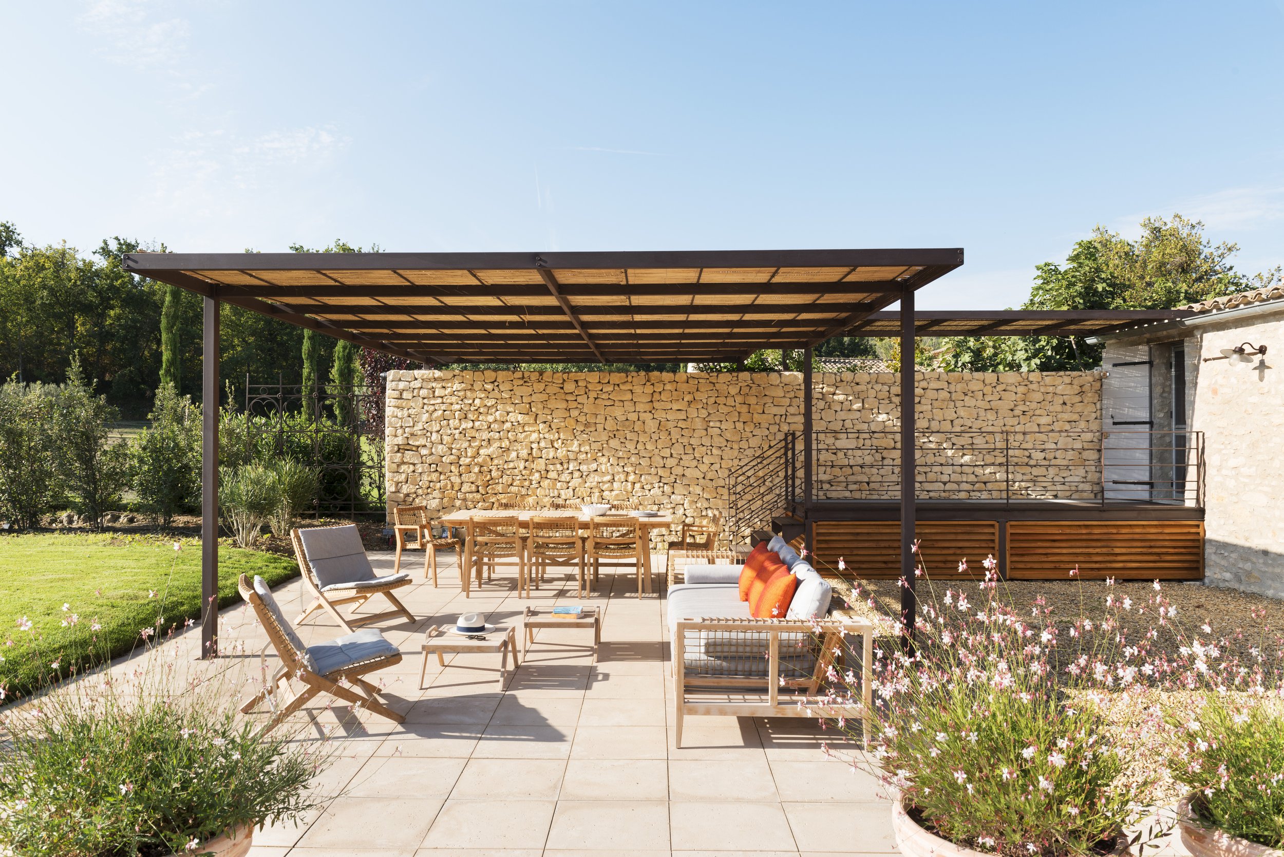 View of the covered veranda with a stair and walkway into the back of the house and the garden extending to the left.