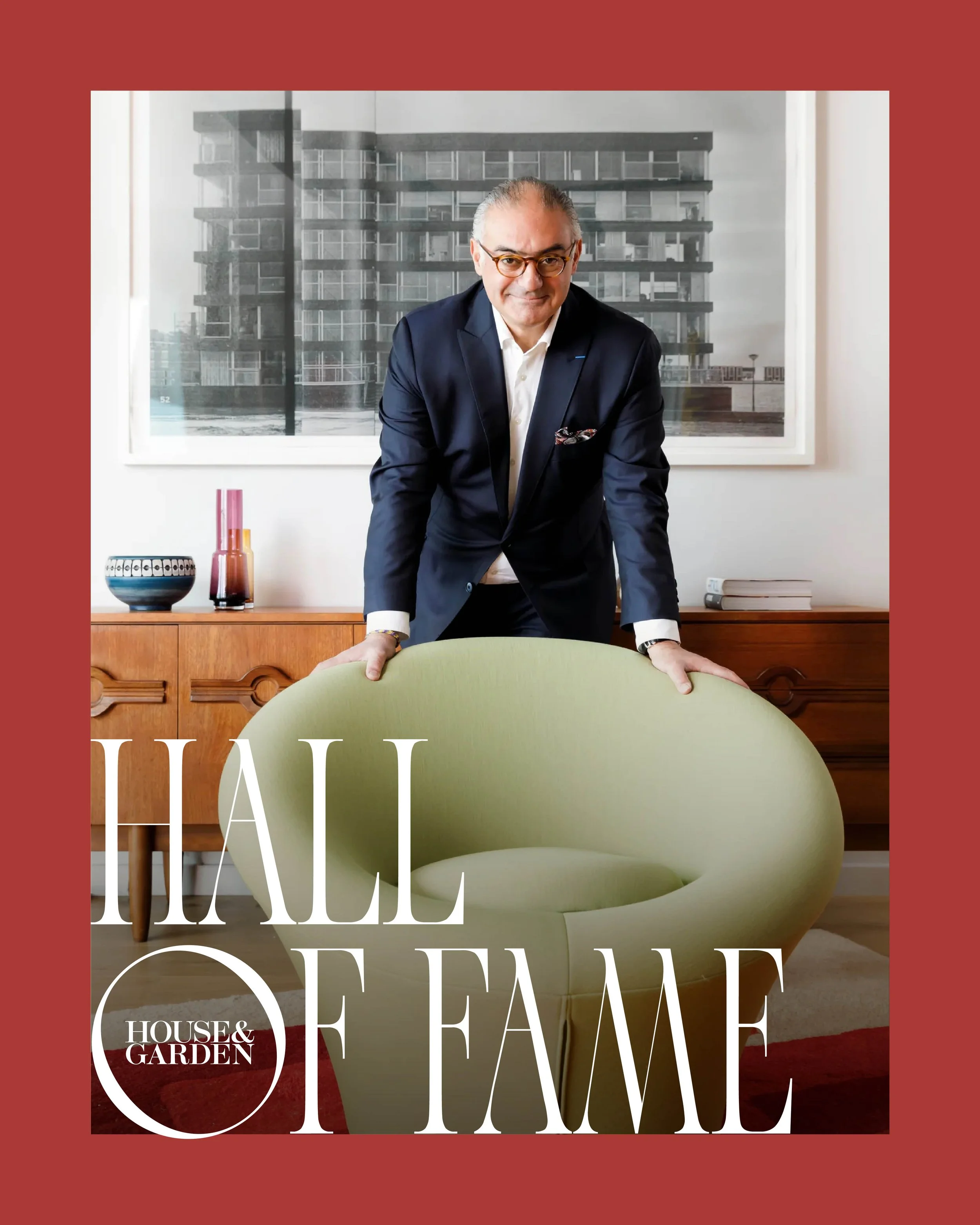 Portrait of architect and designer Rabih Hage, standing in an interior behind a mid-century chair.