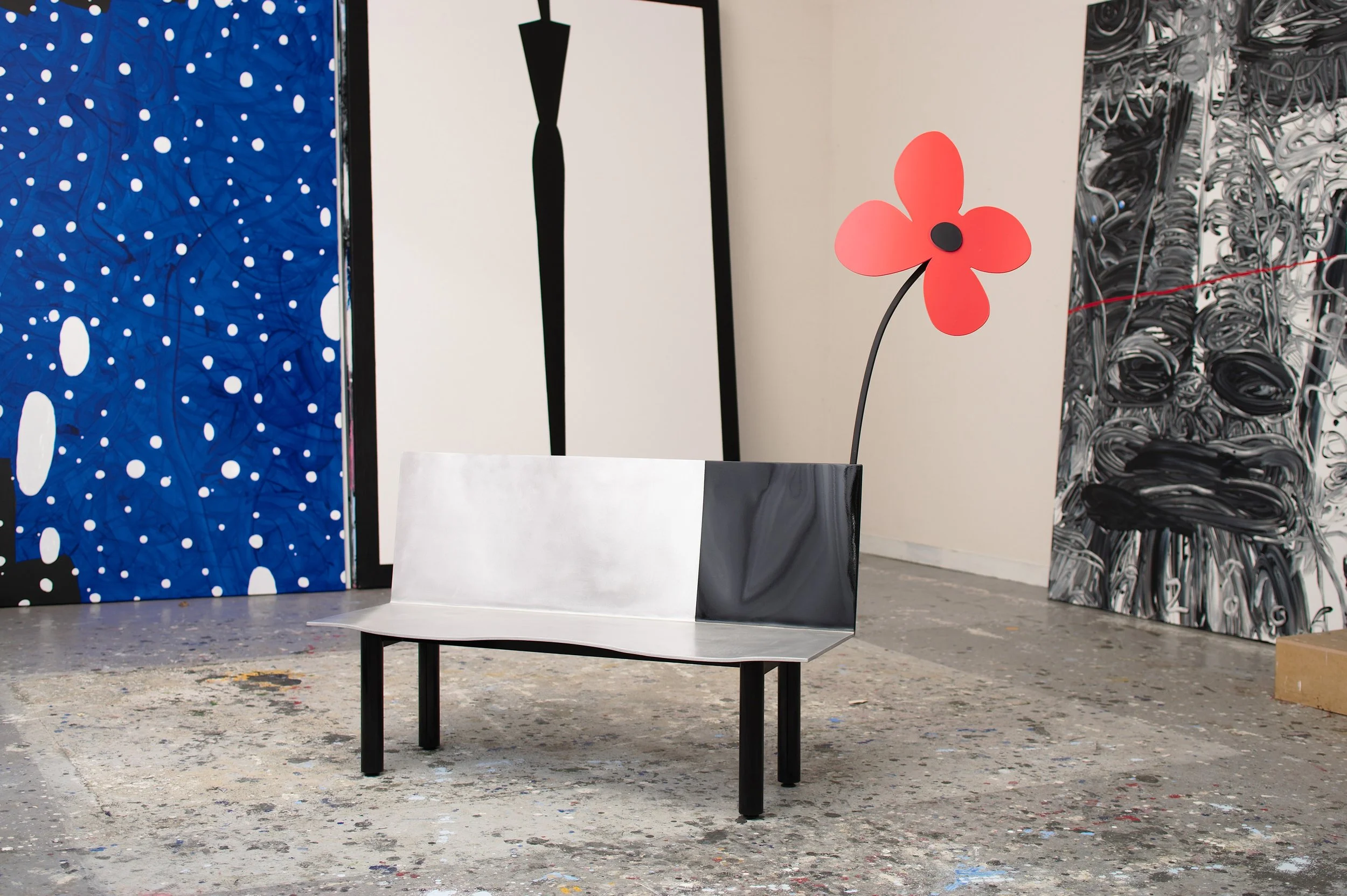 studio photo of the red flower bench in front of some of his paintings.