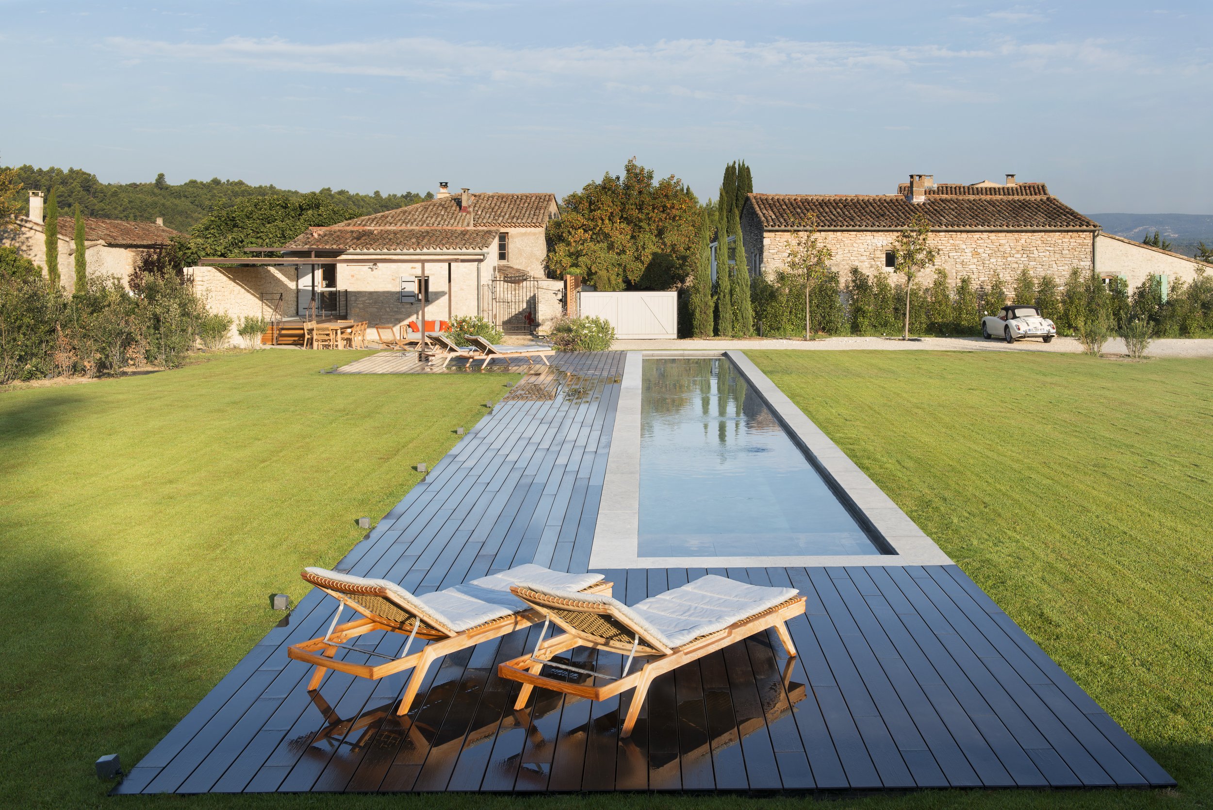 A view looking back towards the house and terrace from the end of the 22 metre linear pool, surrounded by a verdant lawn.