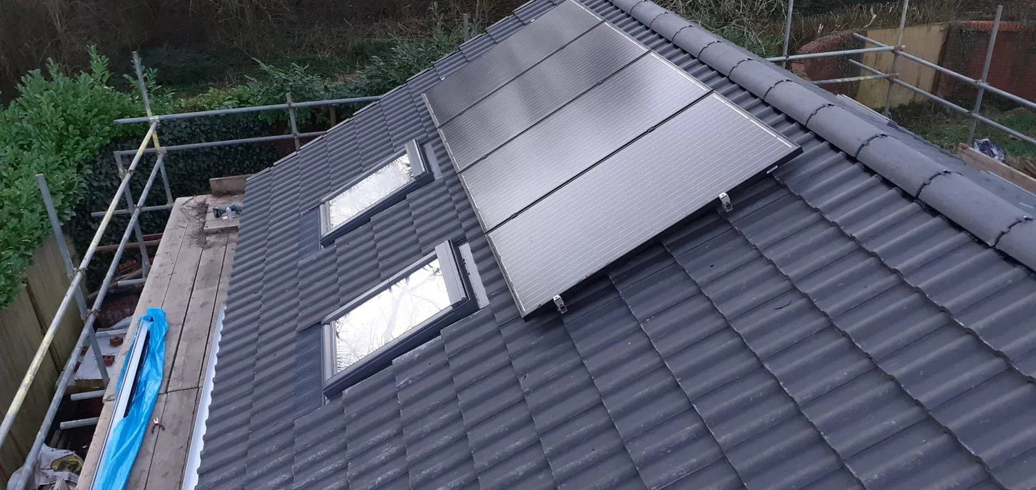 Aerial view of a house roof with skylights and solar panels, surrounded by scaffolding