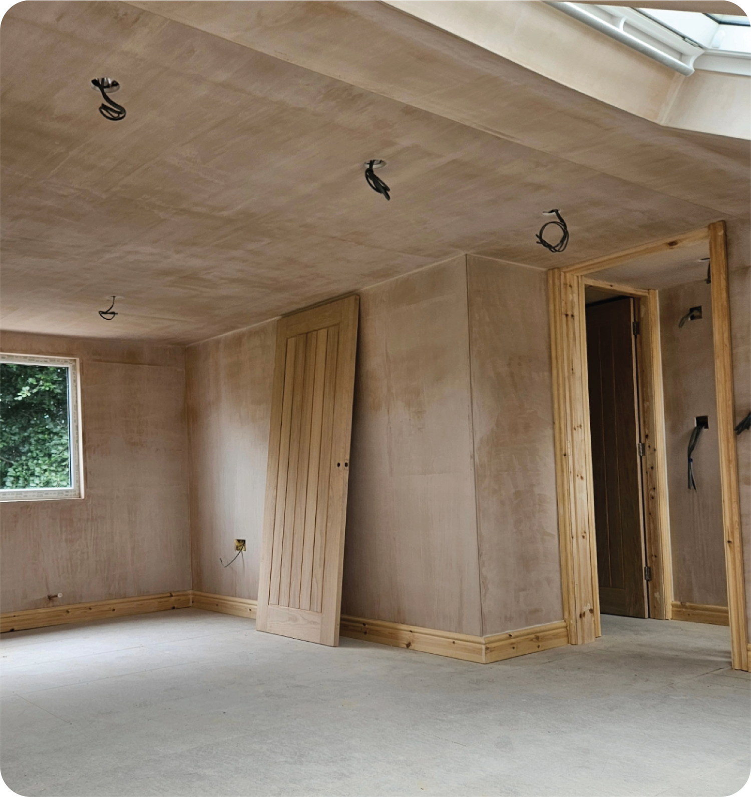 Unfinished loft room under construction with bare walls, exposed wiring and a window