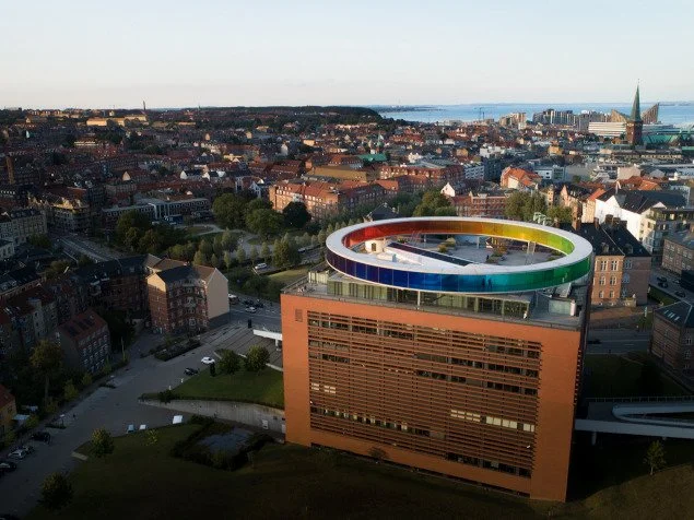 Aarhus cityscape featuring ARoS art museum with a colorful circular skywalk on the roof.