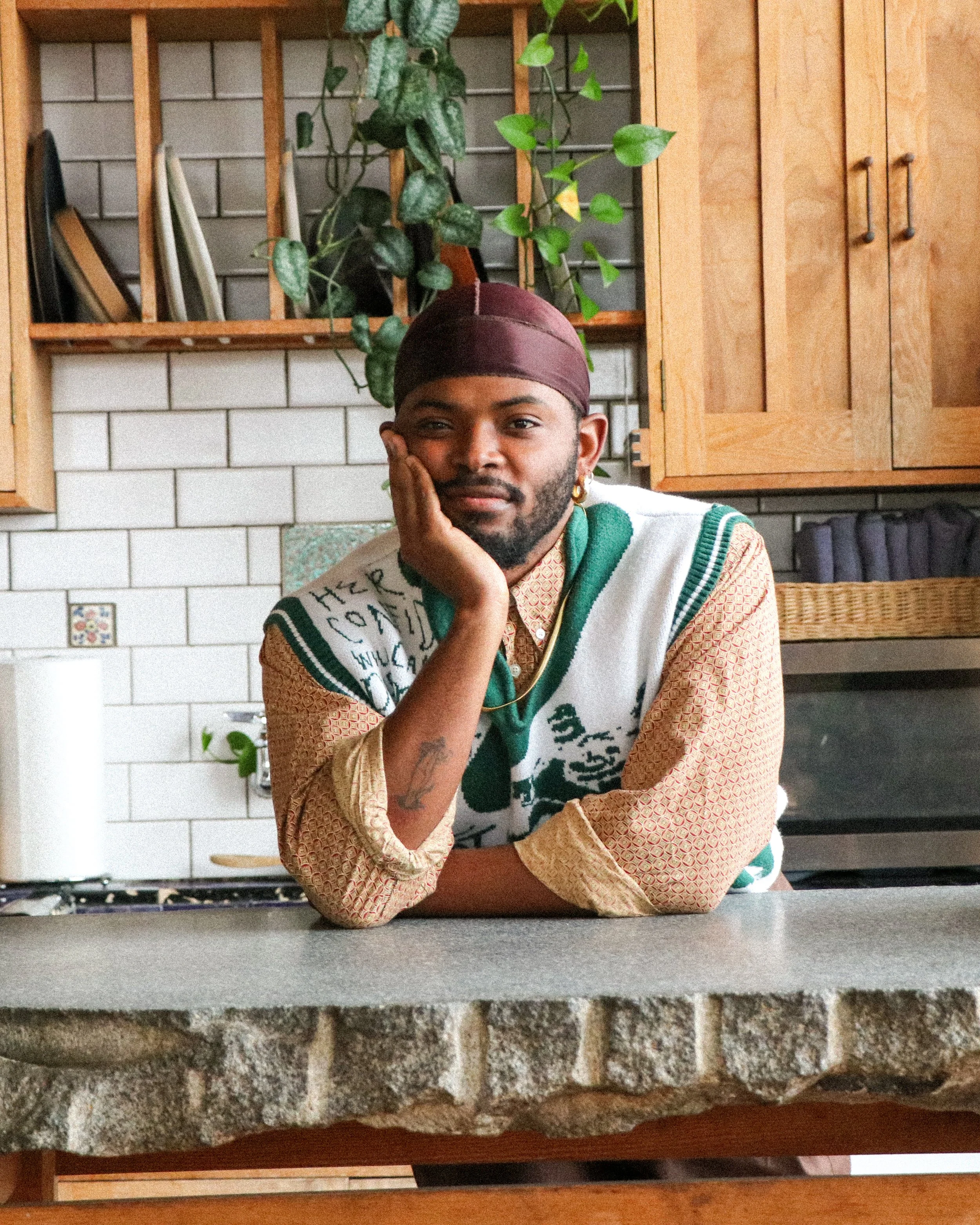 Keanu Jackson LCSW sits at a kitchen counter with his head in his hand staring at the camera