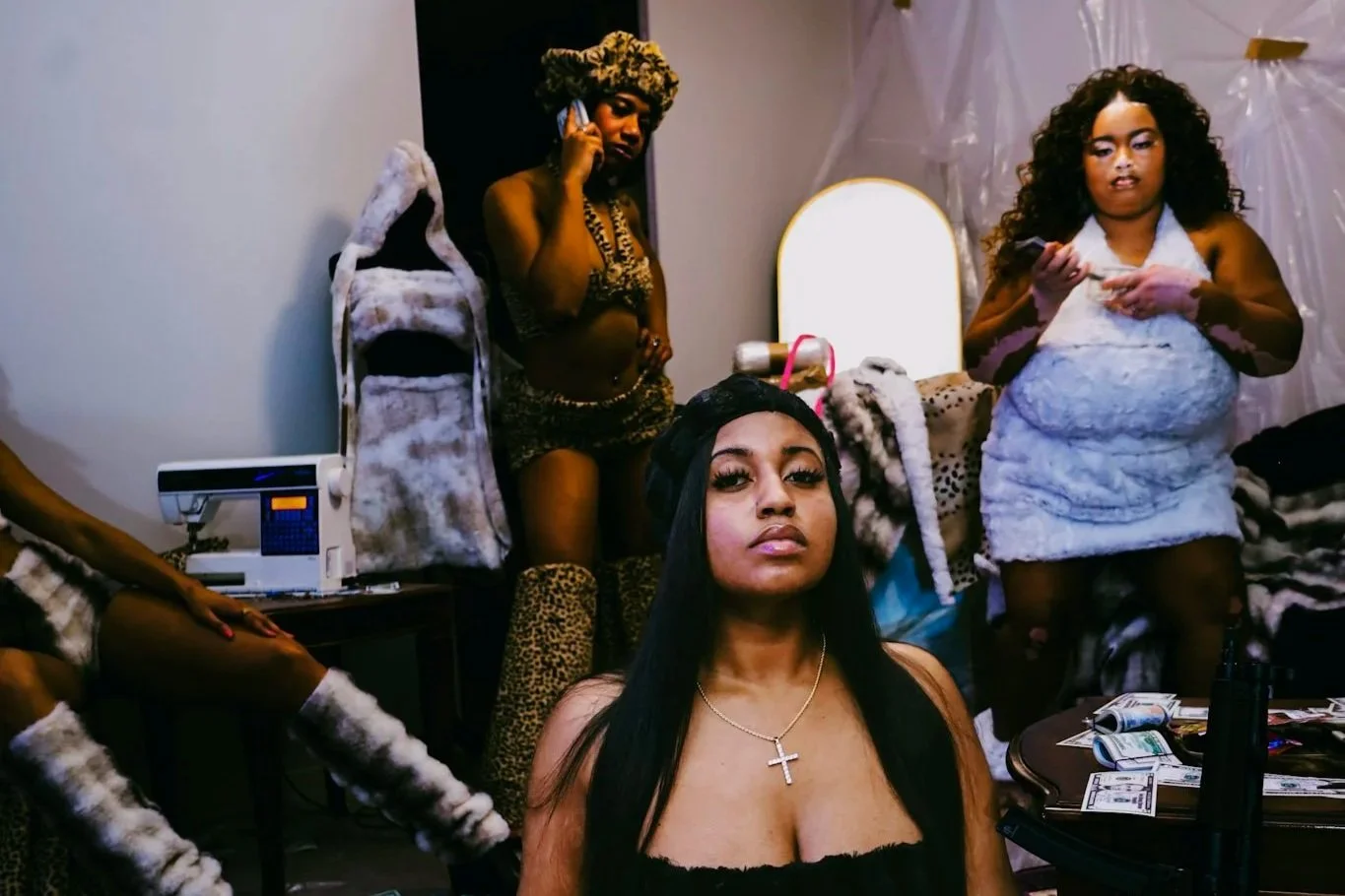 Group of women posing in a dressing room with costumes, makeup, a vanity mirror, and clothing racks