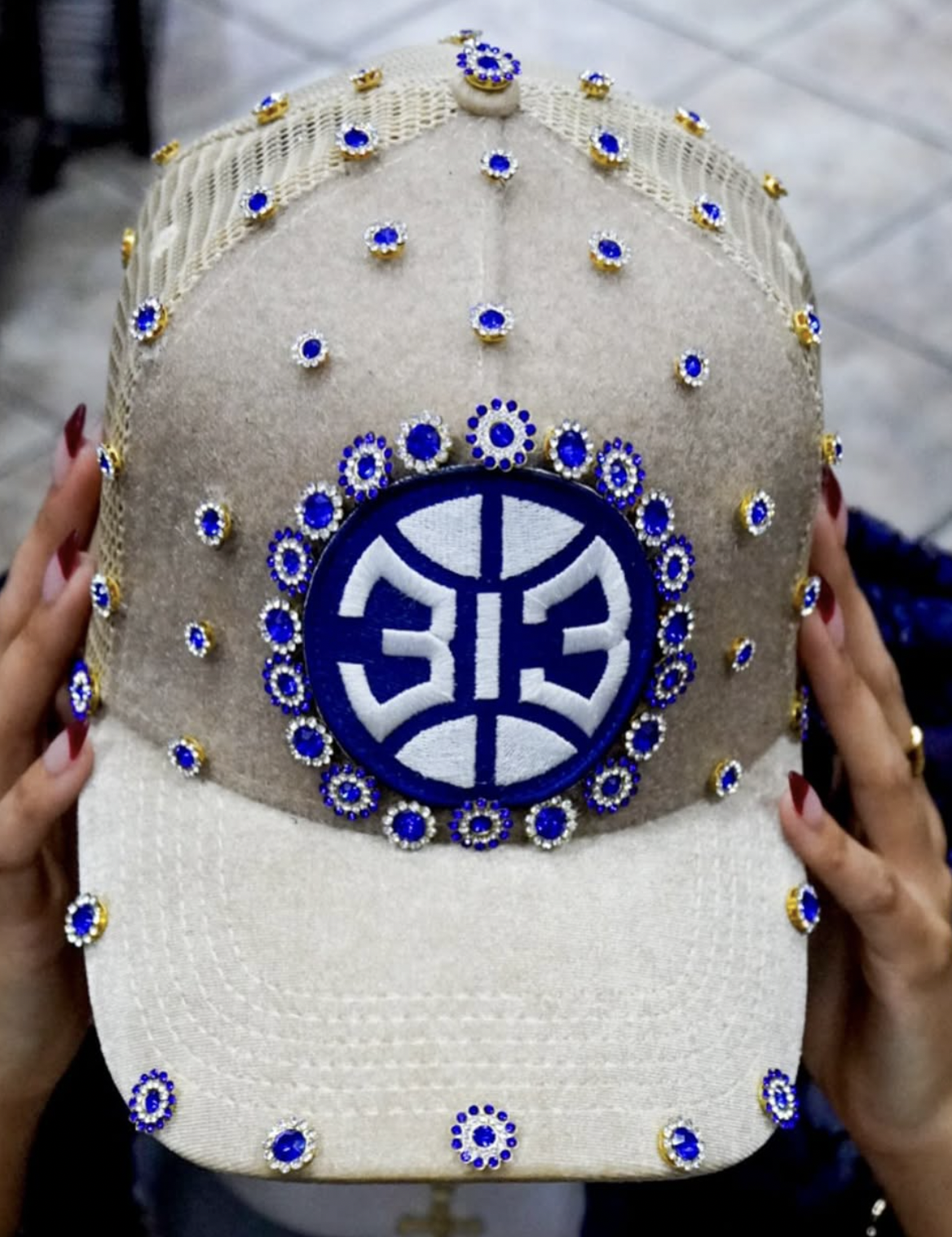 White embroidered baseball cap decorated with blue and gold rhinestones and a large circular Chinese character emblem