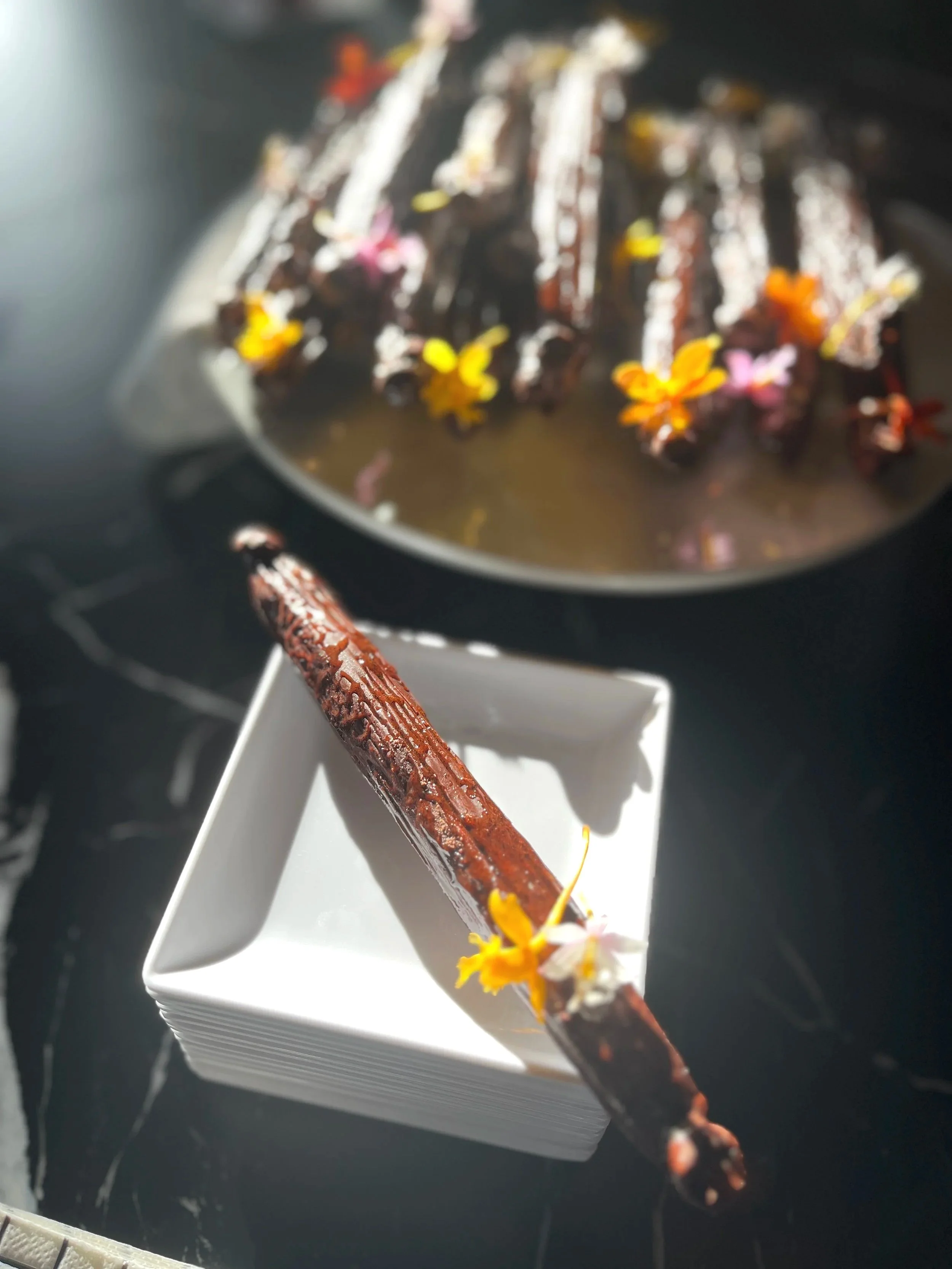 Nō 24 -------- HANDCRAFTED 7" LONG VANILLA BEANS - chocolate coated vanilla cream and wafer interior.  finished with miniature edible orchids that taste like citrus.
Special and unique dessert.  
Minimum orders of 24.
$12 ea.