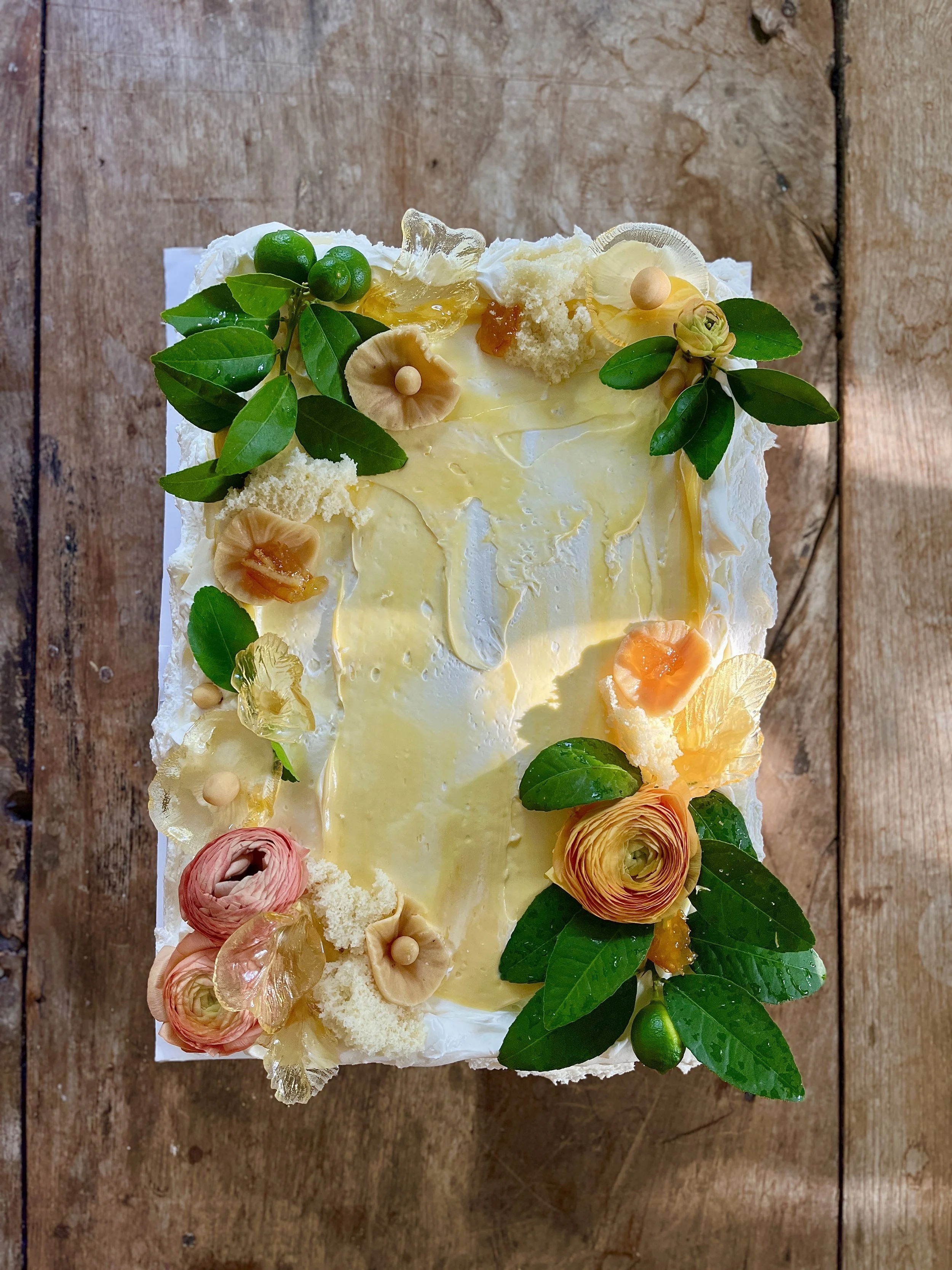 Nō 52 -------- Citrus vanilla Chantilly cream and marzipan landscape cake.

seasonal blossoms, young citrus, natural lemon leaves and stems, sugar gossamer leaves, coral sponge cake lumps and lemon curd.  Size shown made for 25 guest.  Custom sizes a