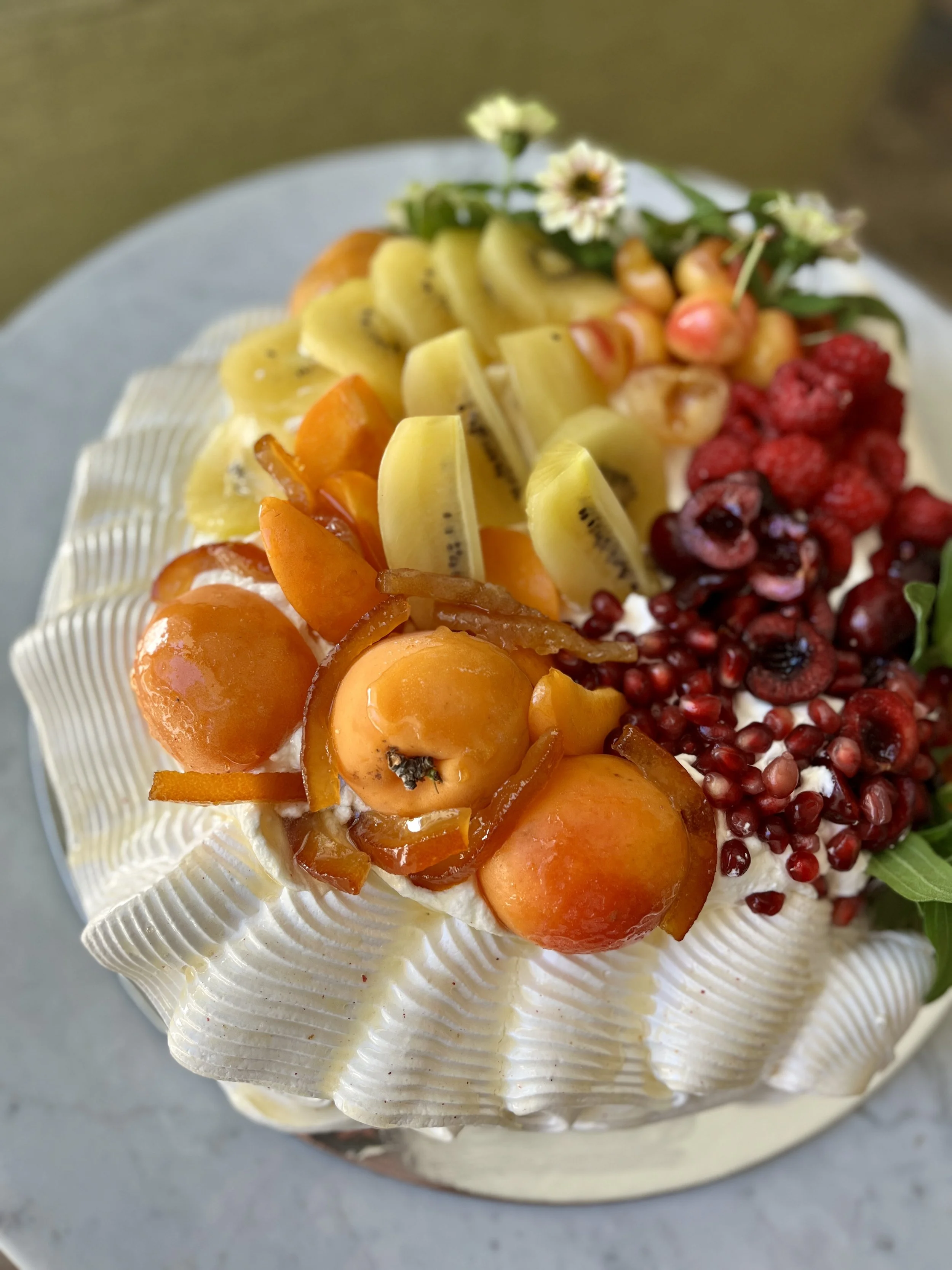 Nō 19 -------- RIBBON PAVLOVA -  manipulate French meringue to simulate a ribbon.
Chantilly lemon cream fills the cavity of the Pavlova shell. Topped with assorted fruits hand brushed with orange reduction syrup and sprinkle with lemon crystals. Meri