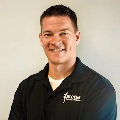 Portrait of a man wearing a black polo shirt with a logo.