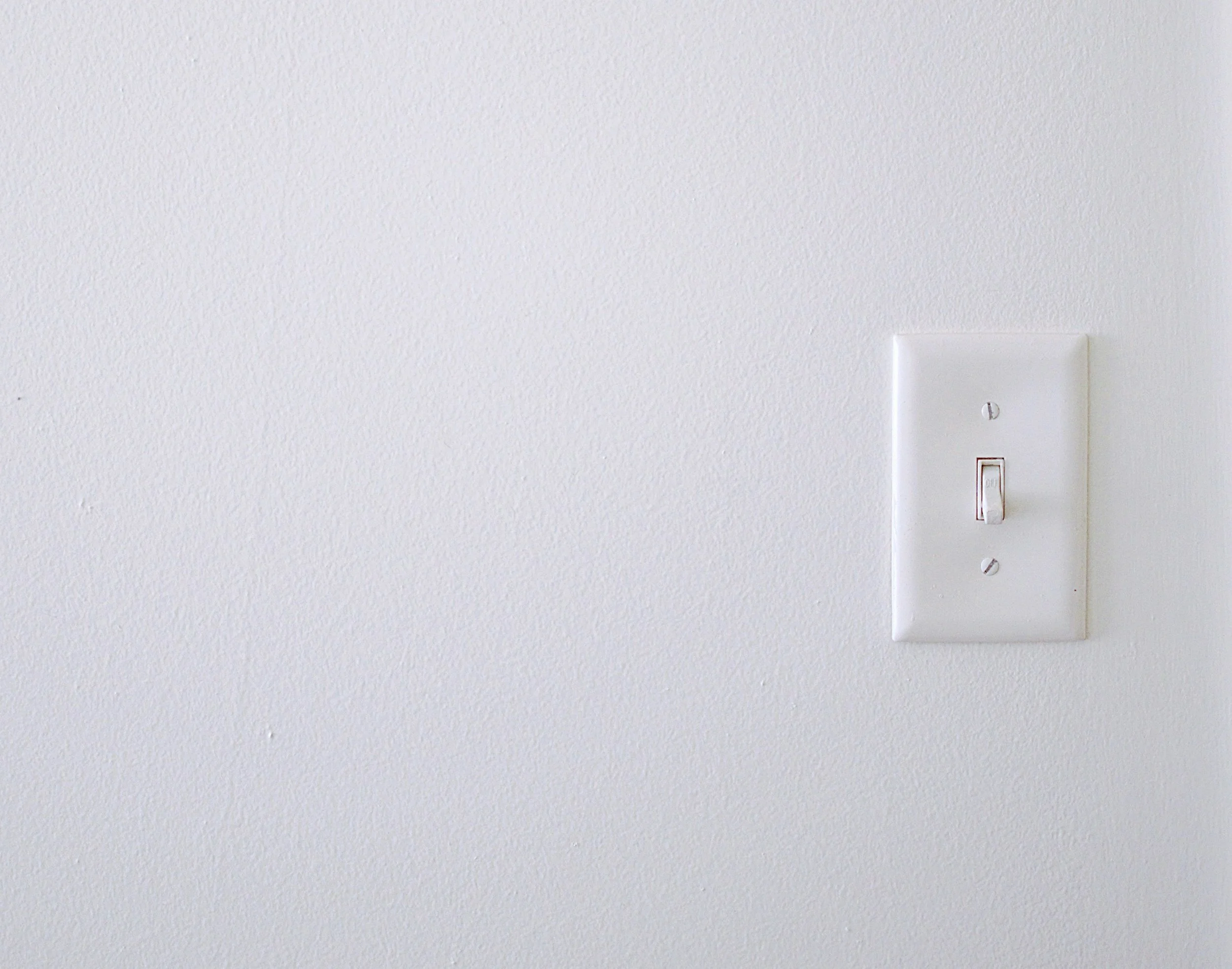 Close-up of a white wall with a single light switch.