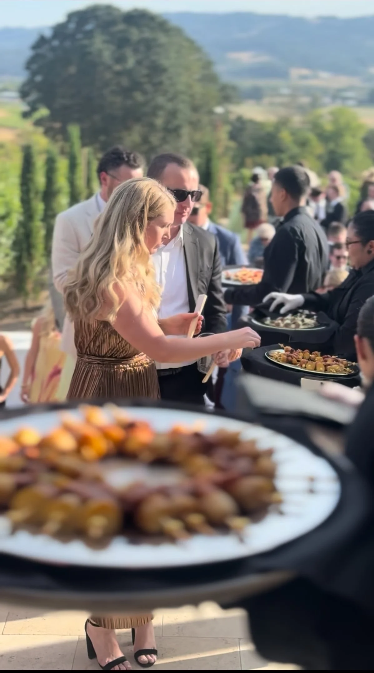 People at an outdoor event serving appetizers and food from trays.