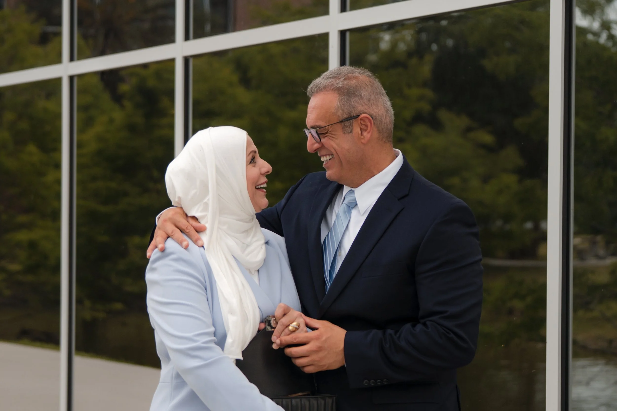 College graduate's mother and father look at each other lovingly after their son's FIT graduation