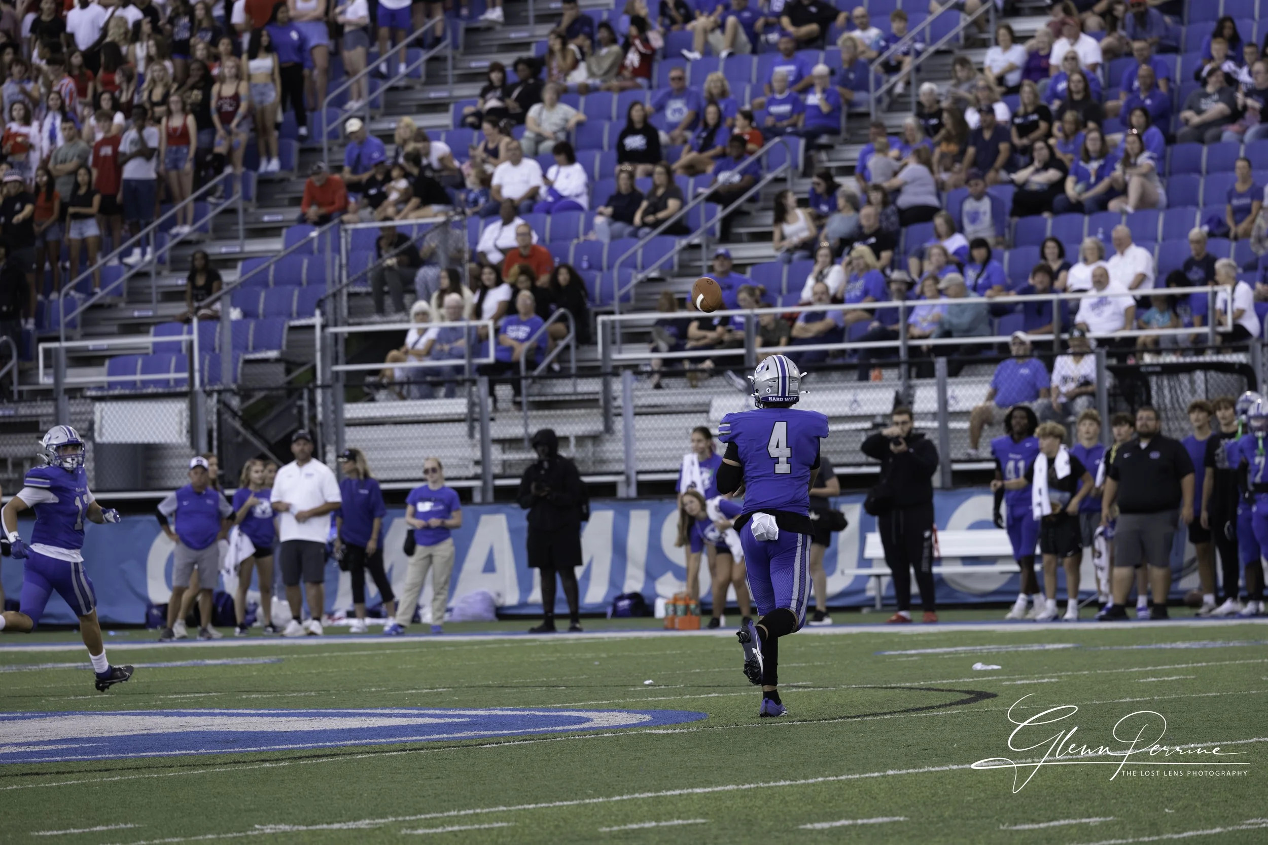 A football game in progress with players on the field and spectators in the stands.