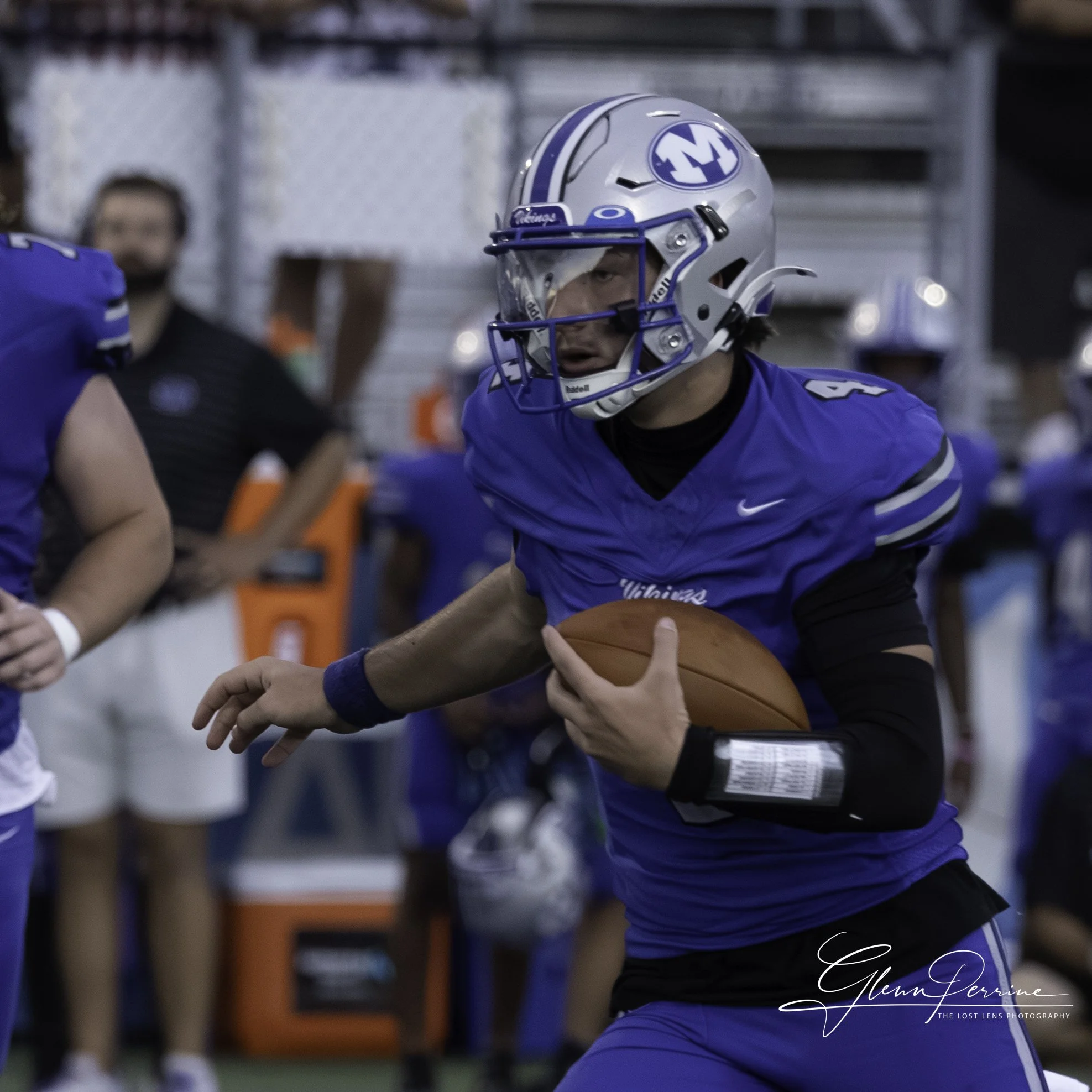 American football player in blue uniform wearing a helmet holding a football during a game.