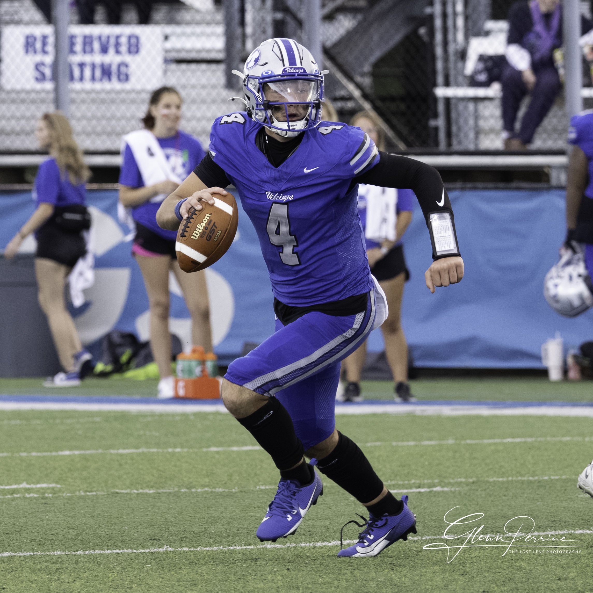 An American football player in a blue uniform, number 4, running with the ball on the field during a game.