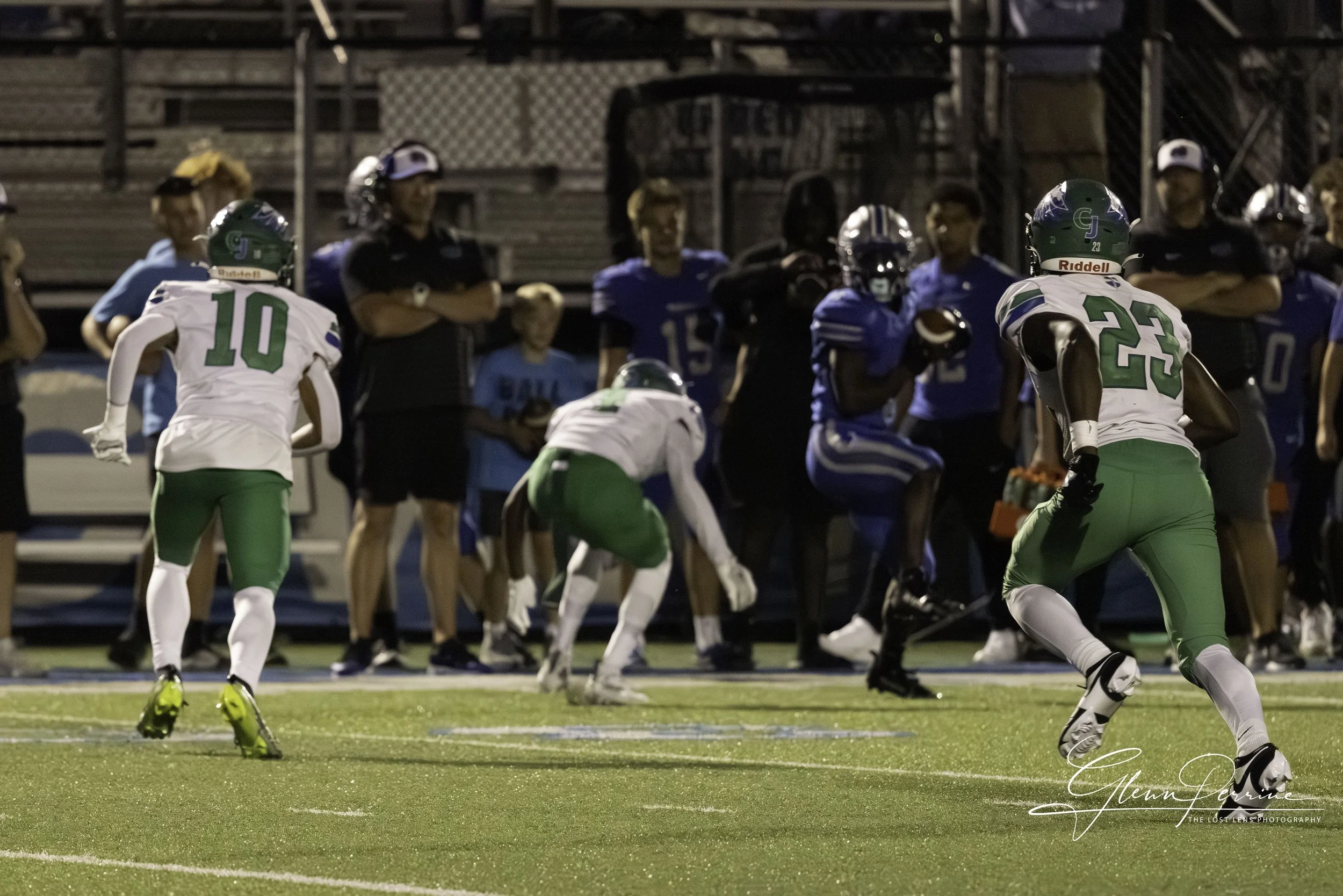 Football players on the field during a game, with some players running and others standing on the sideline.