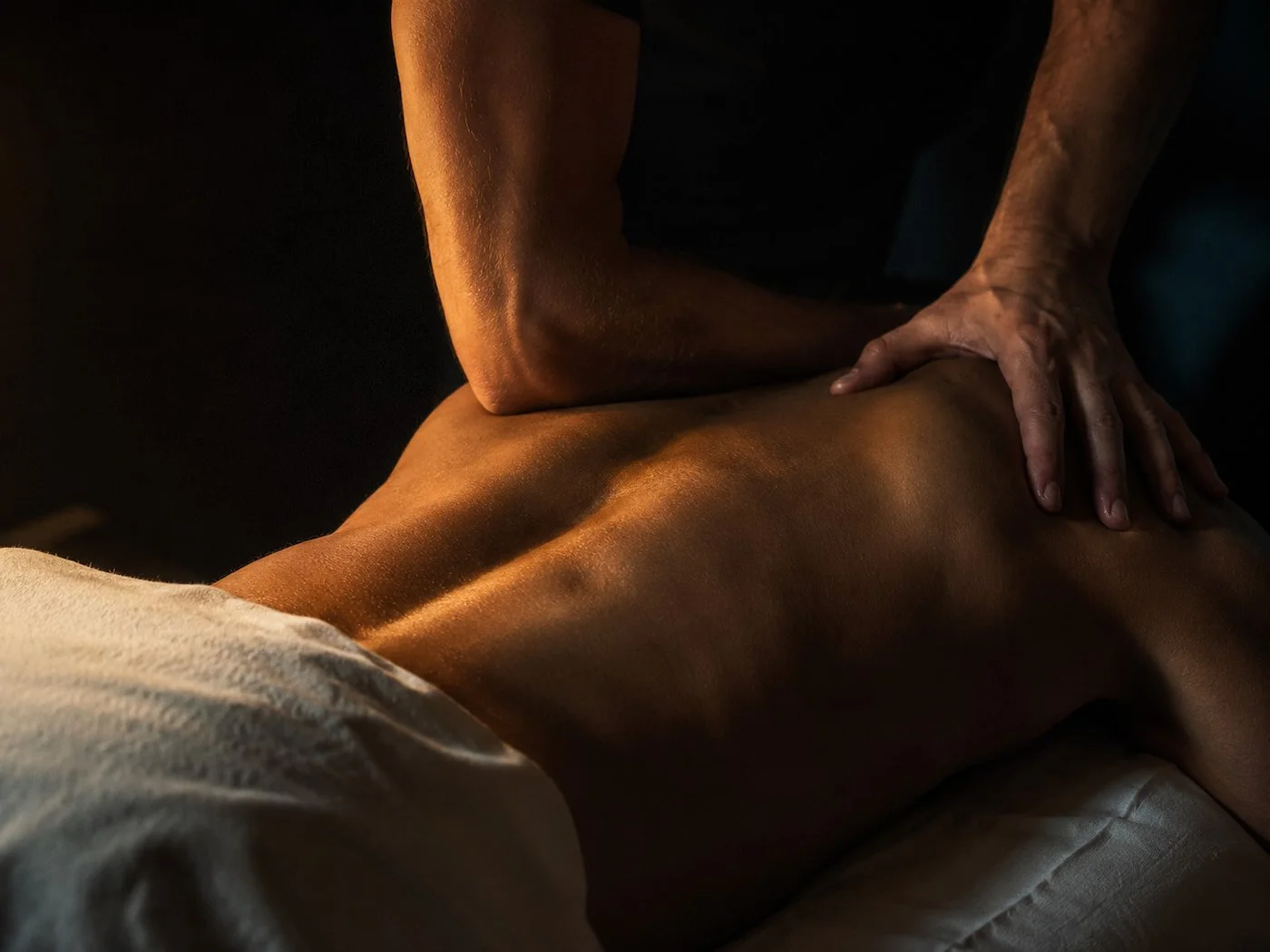 Deep tissue back massage on a muscular client's shoulders and upper back