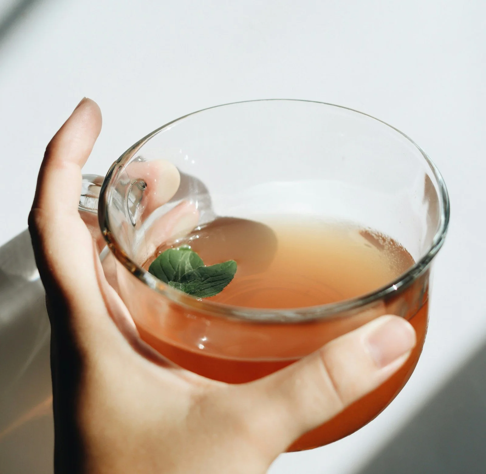 a hand holding a glass mug with a soothing tea