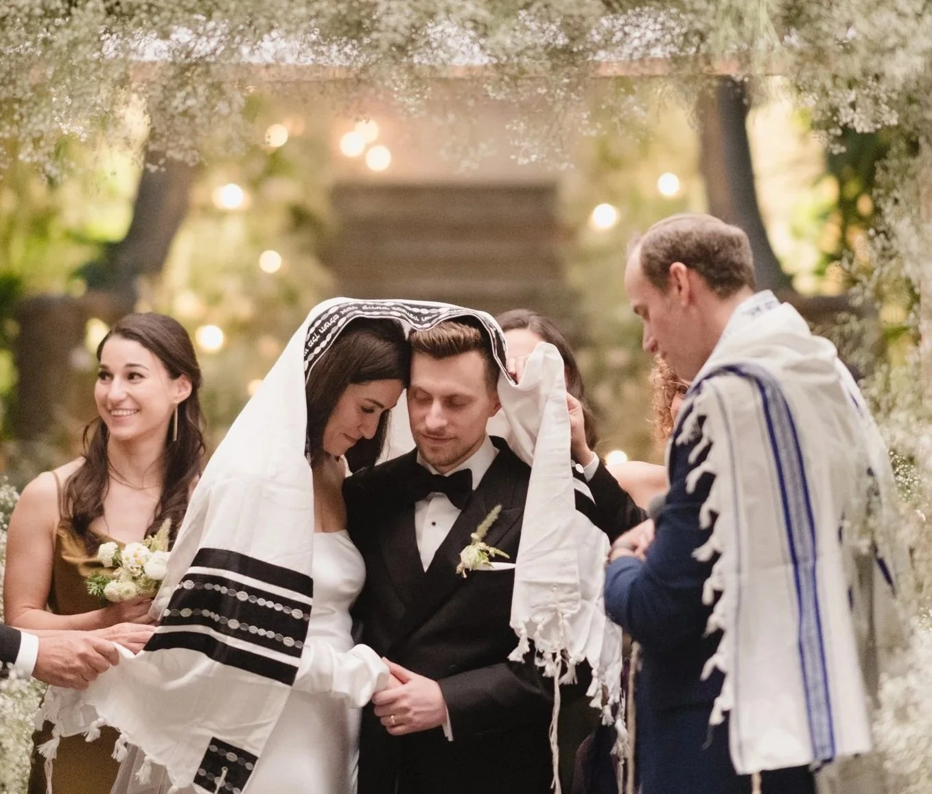 A Jewish wedding ceremony with the bride and groom under a chuppah, surrounded by friends and family.