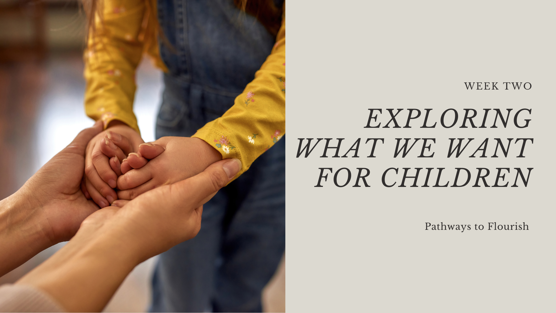 A child holding hands with an adult. The child is wearing a yellow shirt with floral embroidery, and the adult's hand supports the child's hand. The background is blurred.