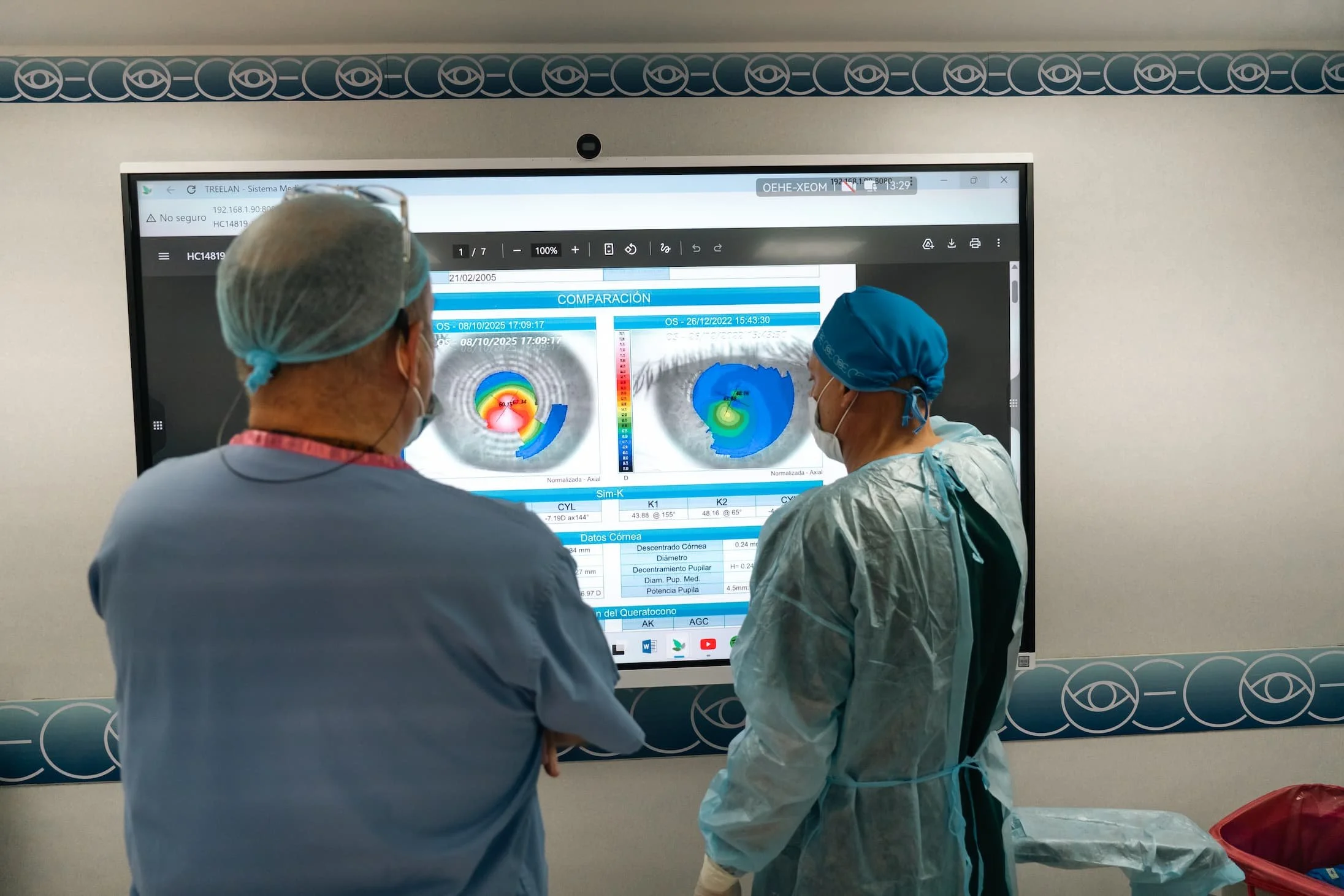 Dos profesionales médicos en un hospital miran una pantalla con resultados y gráficos del cerebro, usando batas y gorros quirúrgicos.