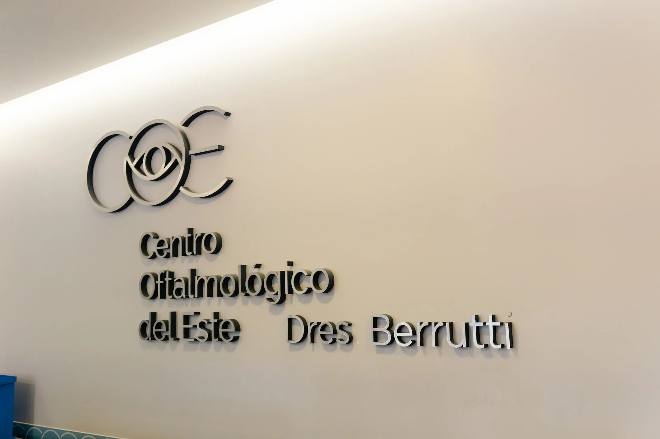 Se ve el logotipo del Centro Oftalmológico del Este, con un símbolo de un ojo estilizado, y el texto en español y en inglés que dice 'Centro Oftalmológico del Este' y 'Dres. Berutti' en una pared blanca.