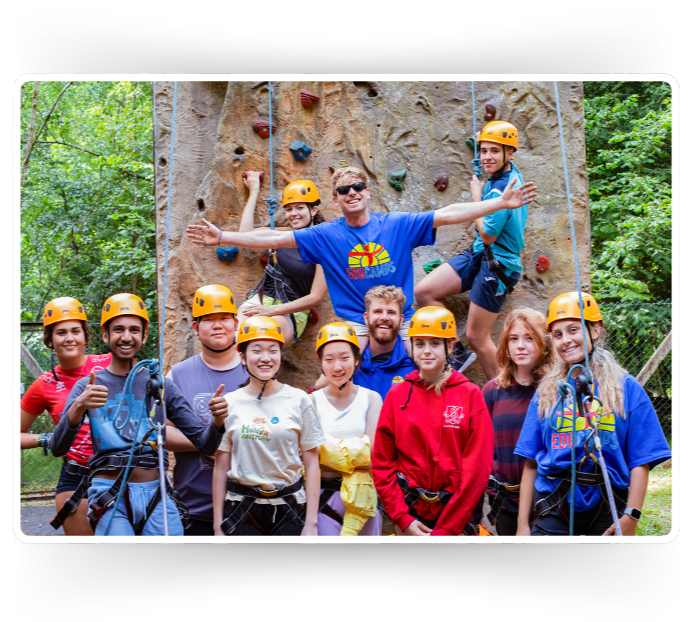 A team photo featuring the team at Educamps Adventures, in front of the climbing wall at Foxlease Park in the New Forest