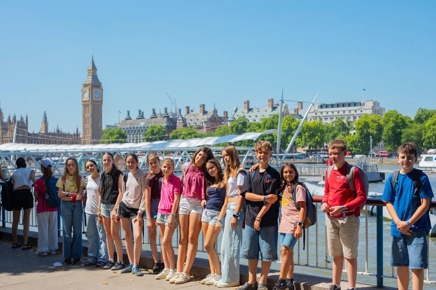 Group with suitcases and backpacks standing outside near Big Ben in London on a sunny day.