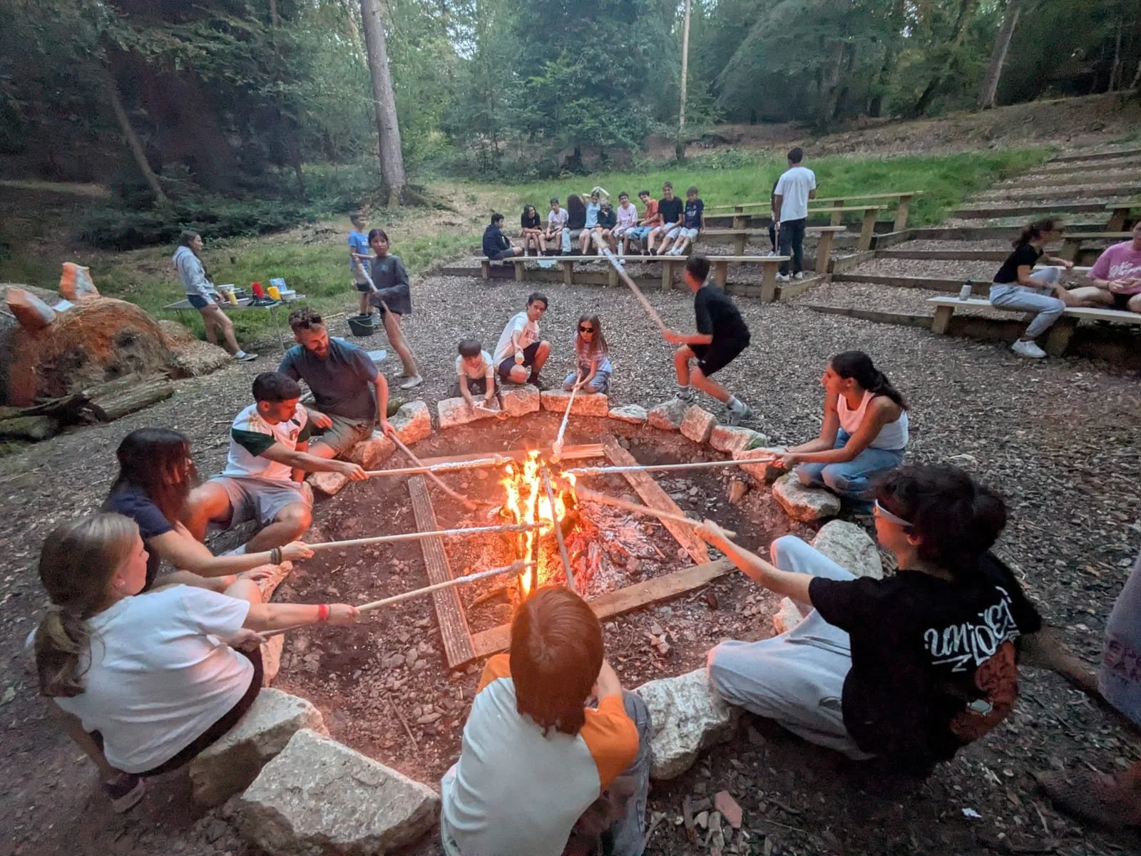 People around a campfire roasting marshmallows at night.