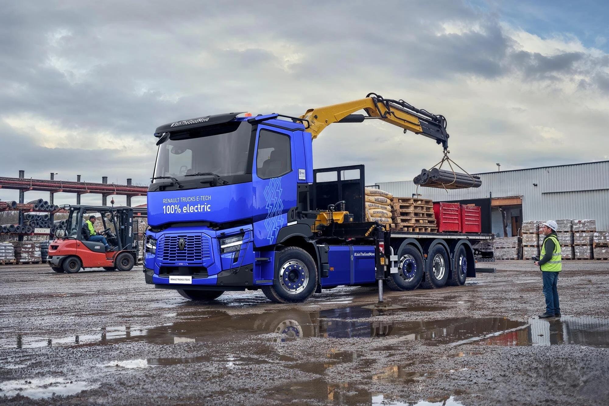 Renault Trucks E-Tech C Elektro-LKW mit Ladekran im Baustelleneinsatz beim Verladen von Rohren für moderne Tiefbau- und Infrastrukturprojekte.