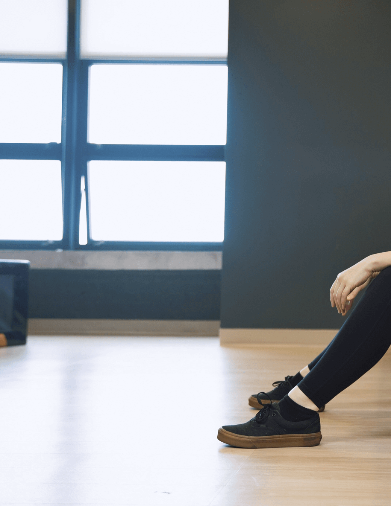 People sitting on chairs in a room with large window and wooden floor.
