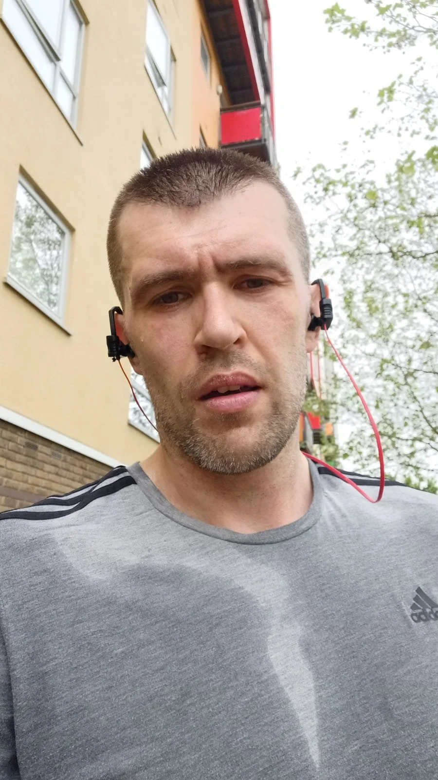 Black-and-white portrait of a person wearing a wide-brimmed hat and a patterned shirt, with their face partially obscured by the hat.