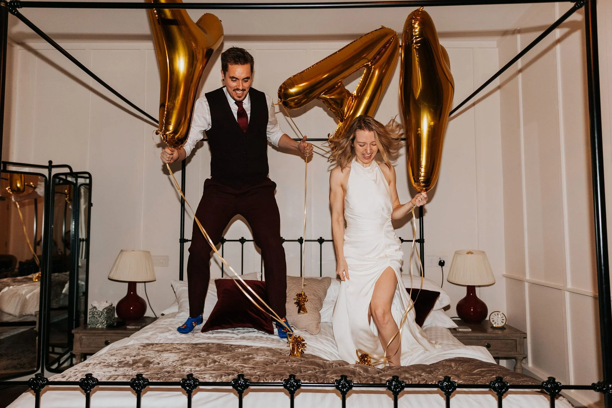 couple jumping on bed with balloons